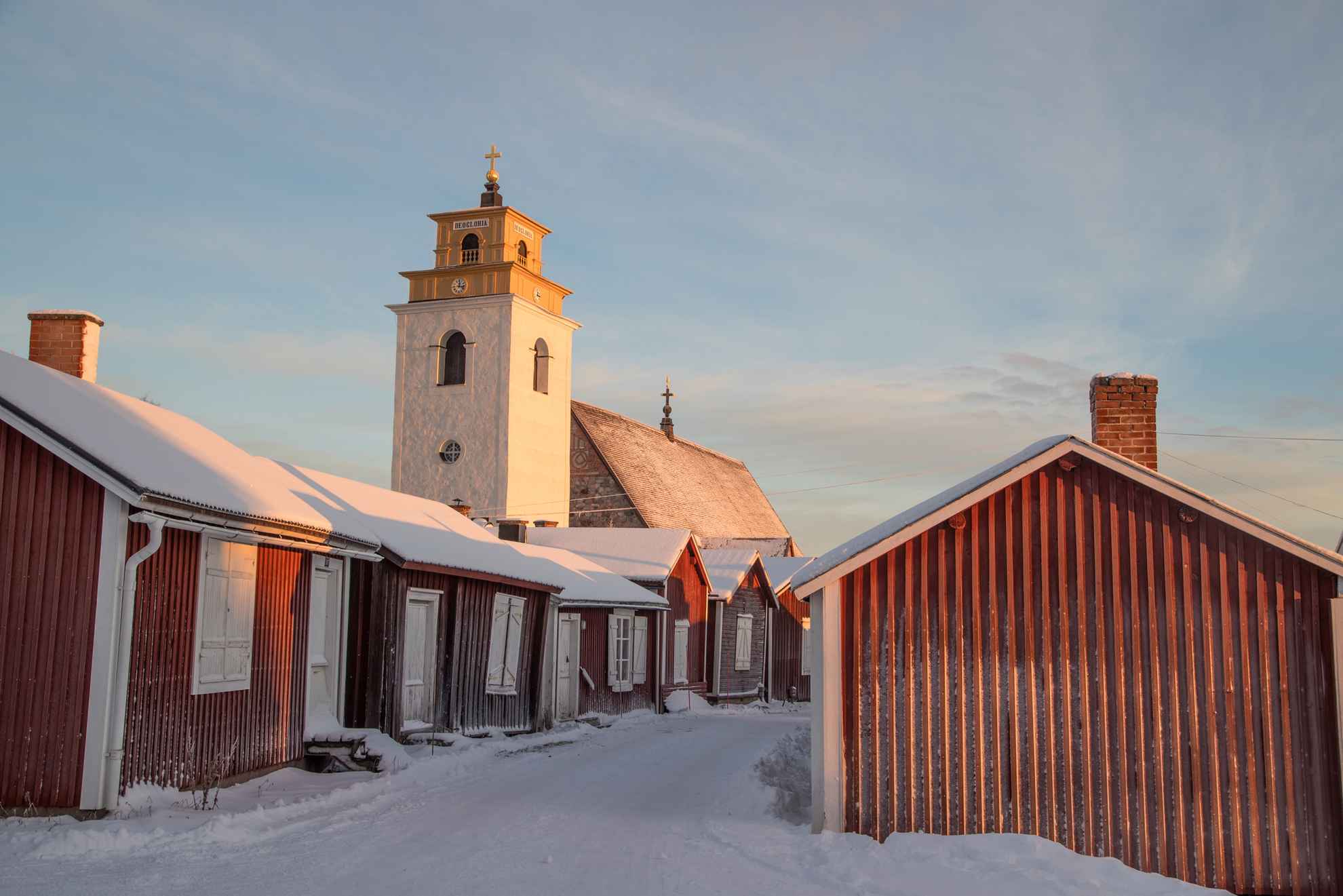 Rote Häuschen und der weiße Kirchturm in der Kirchenstadt Gammelstad im Winter.