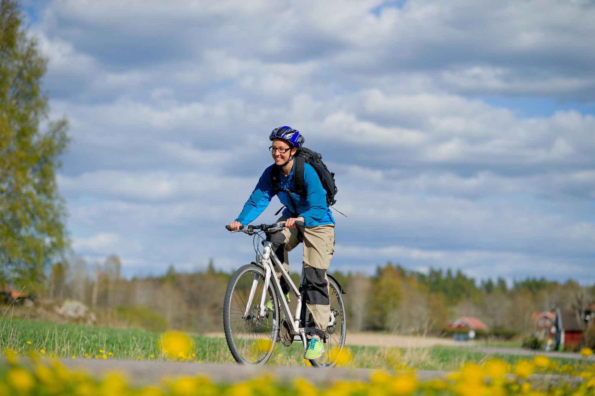 Eine Person mit Helm, die in der Landschaft von Östergötland Rad fährt.