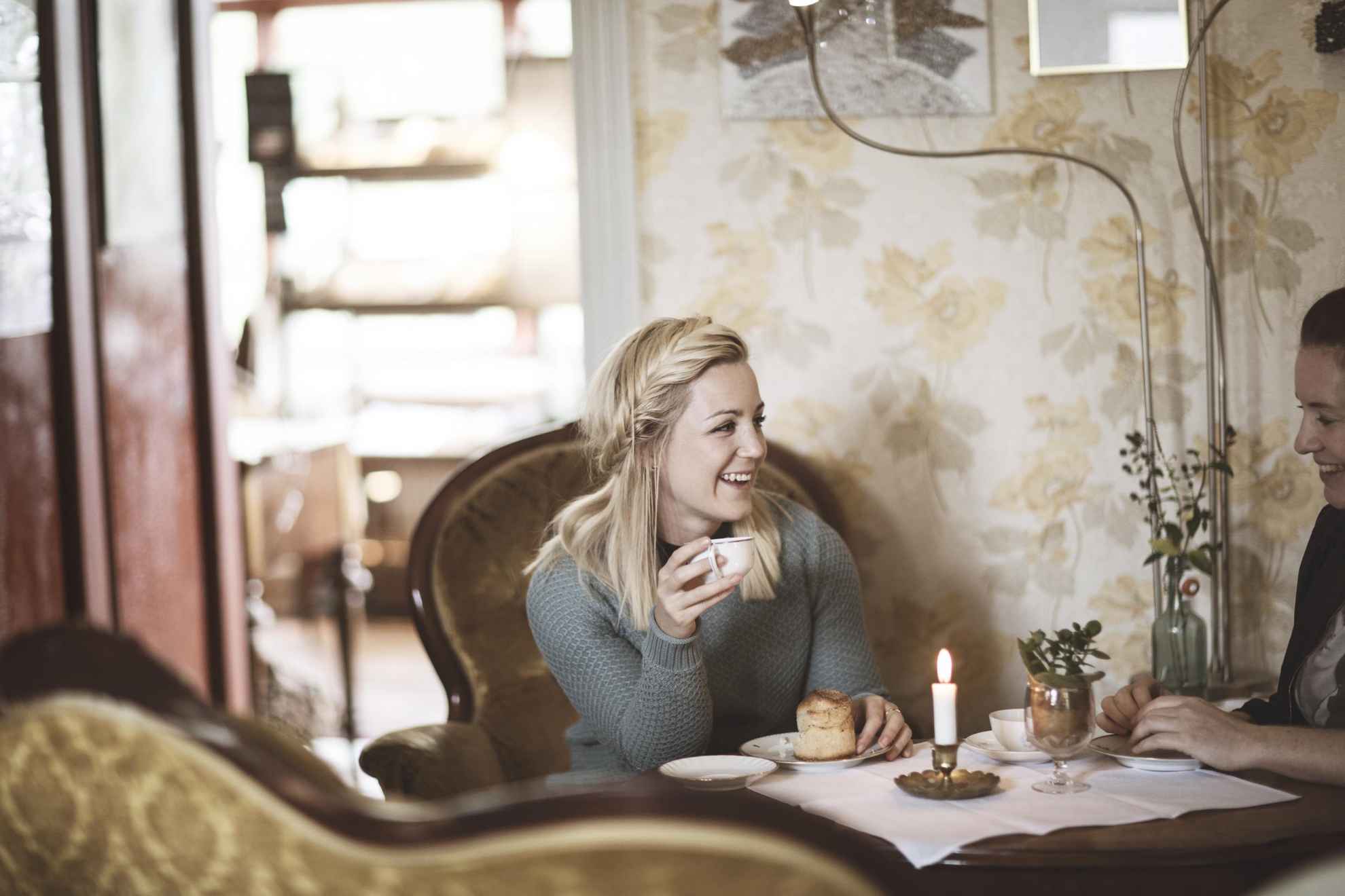 Eine Frau sitzt im Cafe der Nolbygård Bio-Bäckerei in Alingsås und trinkt einen Kaffee und ist eine Zimtschnecke.