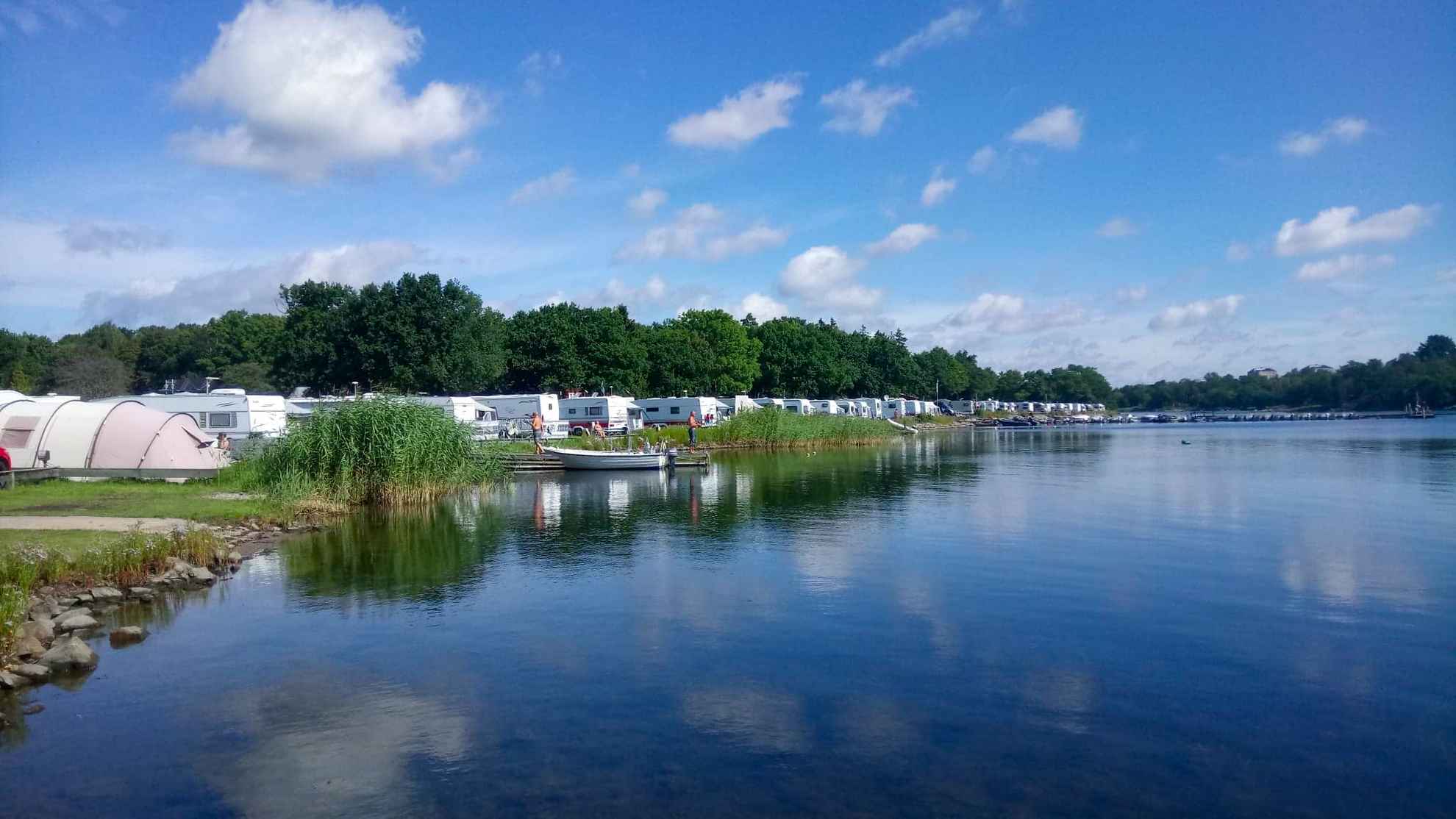 Auf Dragsö Campingplatz stehen Wohnwagen und Zelte in einer Reihe direkt am Wasser.