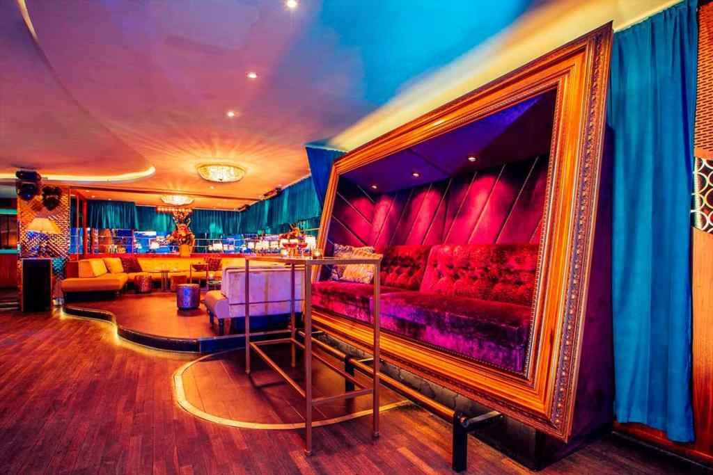 Ein Nachtclub mit Samtmöbeln, Holzböden und blauen Vorhängen.
