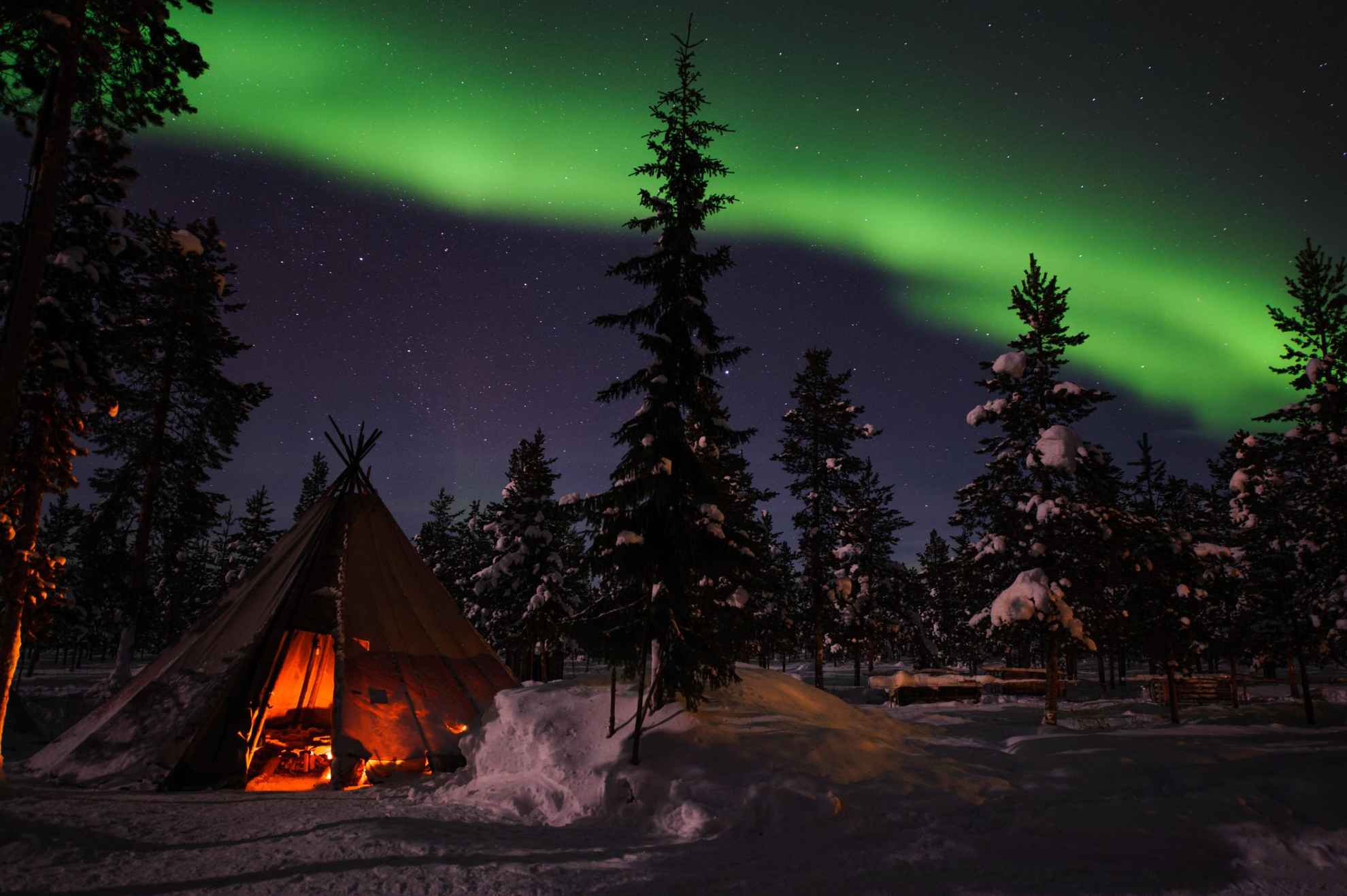 Ein Lavvu im Schnee. Über dem Zelt tanzen Nordlichter am Himmel Schwedisch Lapplands.