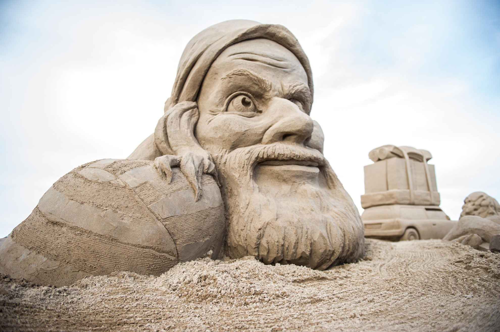 Eine Sandskulptur, die den Kopf eines alten Mannes mit Bart darstellt.
