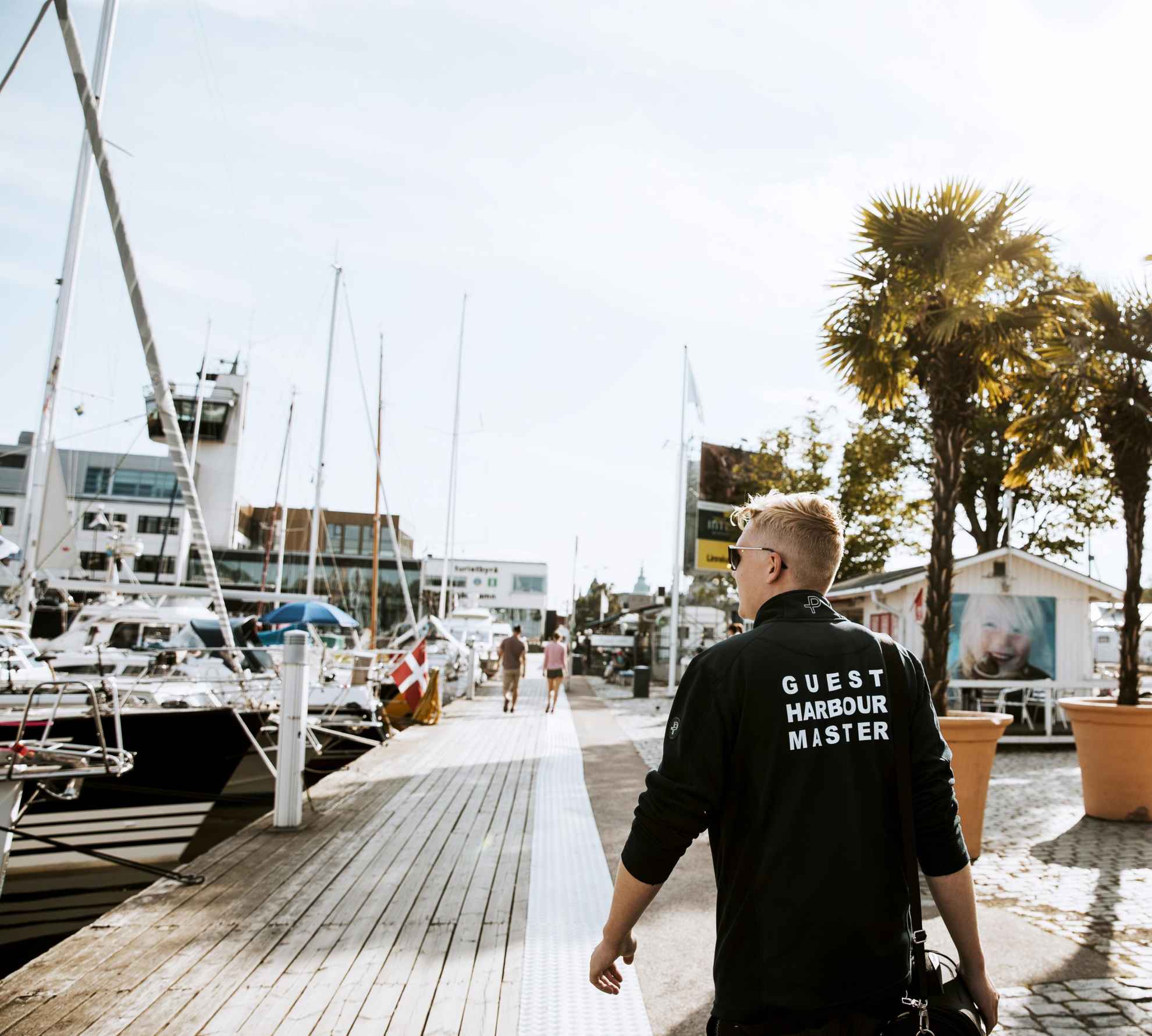 Der Mann mit der Aufschrift „Guest Harbour Master“ auf der Rückseite seines Pullovers geht am Gasthafen von Kalmar die Boote entlang..