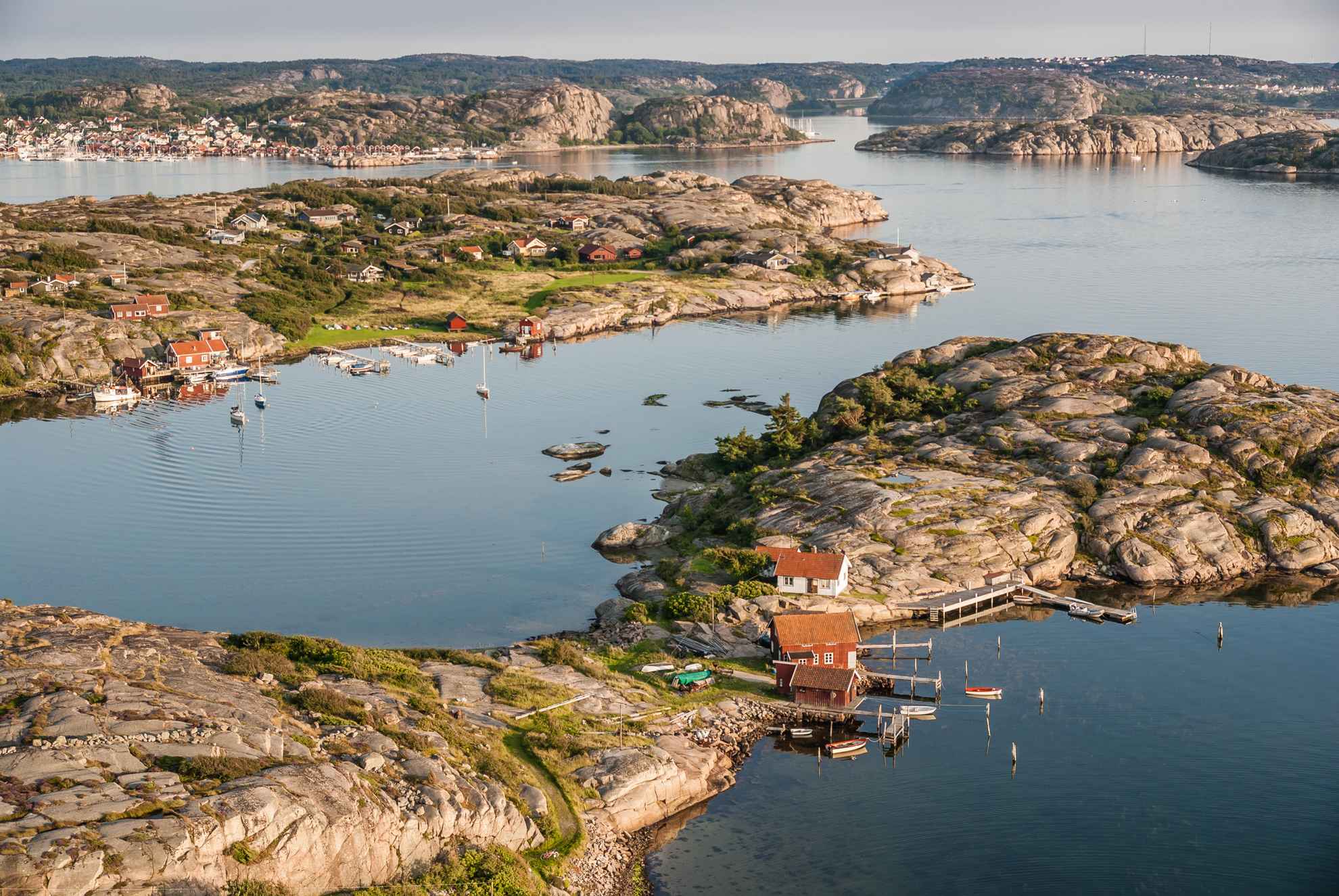 Ein Küstenabschnitt Westschwedens im Sommer. Rote Häuschen stehen auf den kleinen Felseninseln.