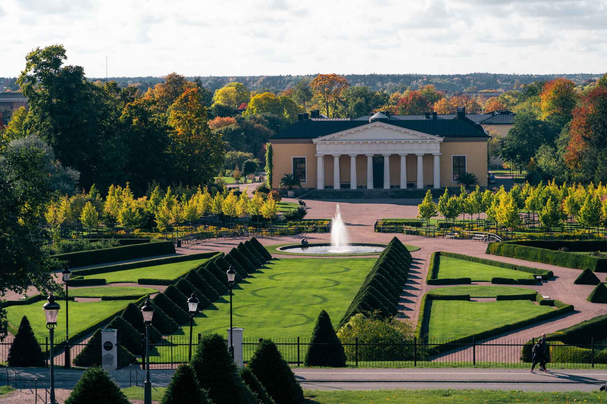 Botanischer Garten in Uppsala. Herbst mit bunten Blättern gemischt mit Grün. Blick über den Barockgarten. Das Gebäude Linneanum im Hintergrund.