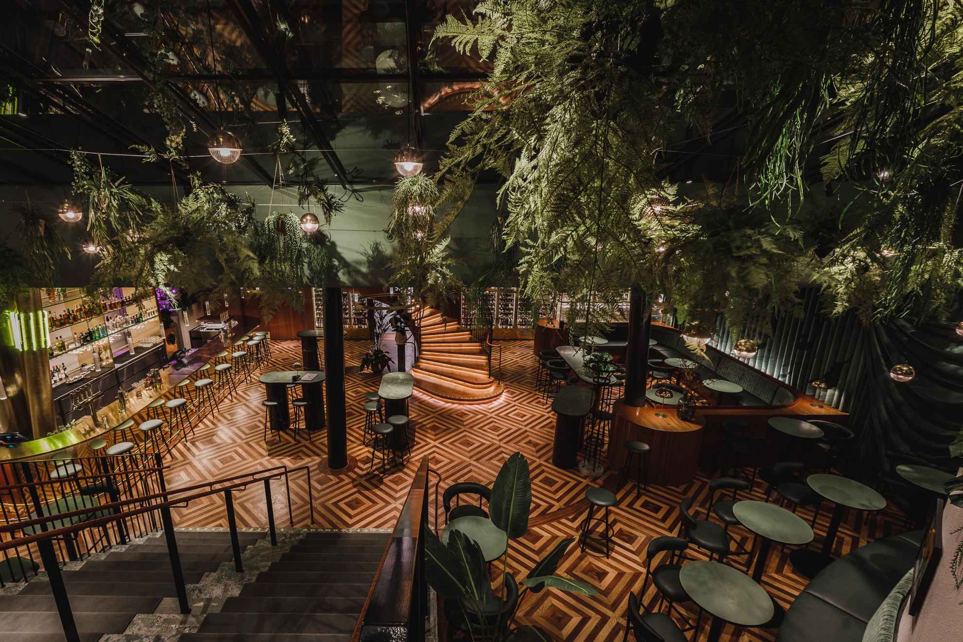 Das Restaurant Brasserie Astoria mit seinen grünen Tischen und Stühlen, der großen Bar und zahlreichen Pflanzen.
