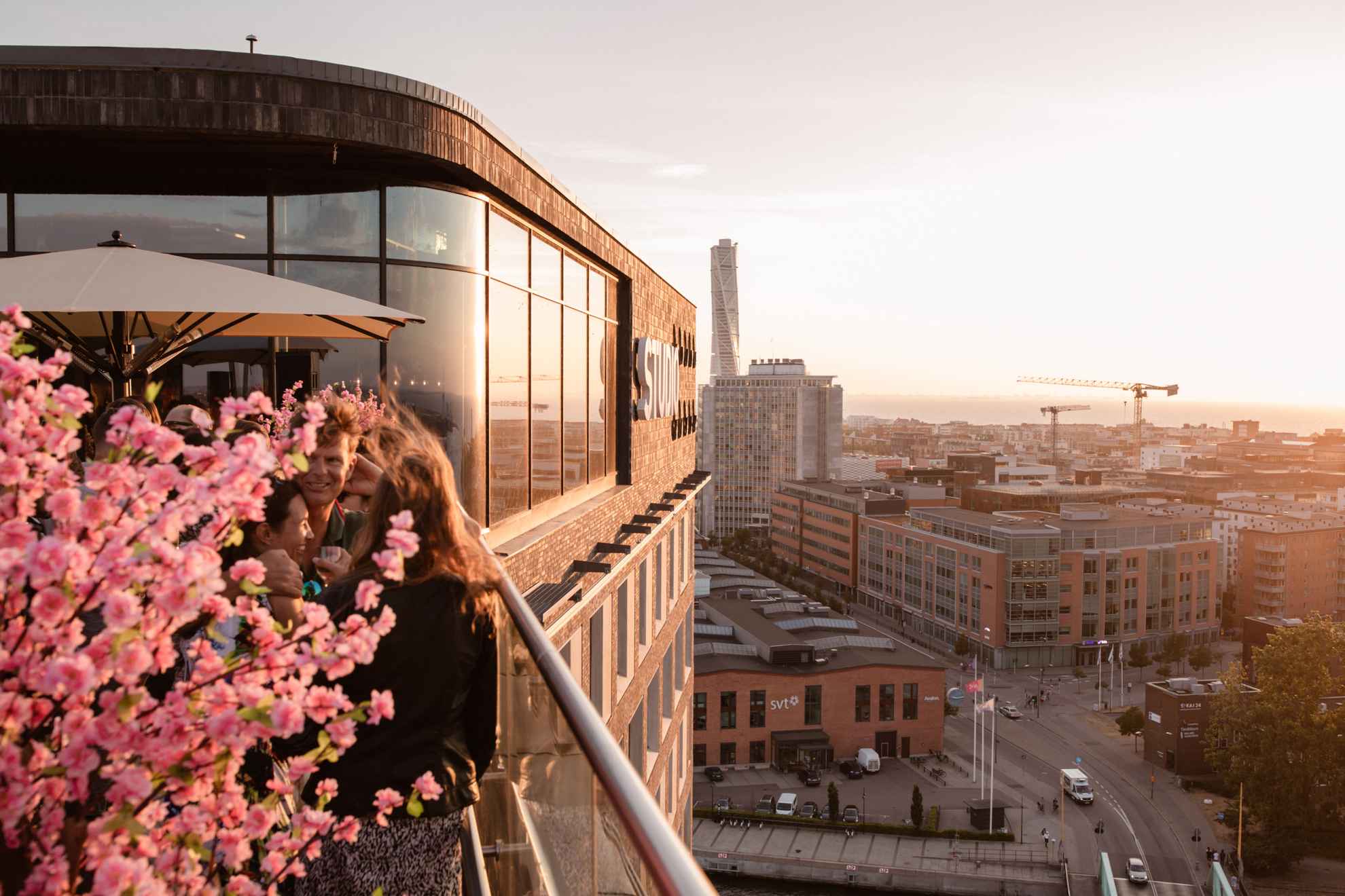 Leute trinken Cocktails auf einer Dachterrassenbar mit Blick über Malmö.