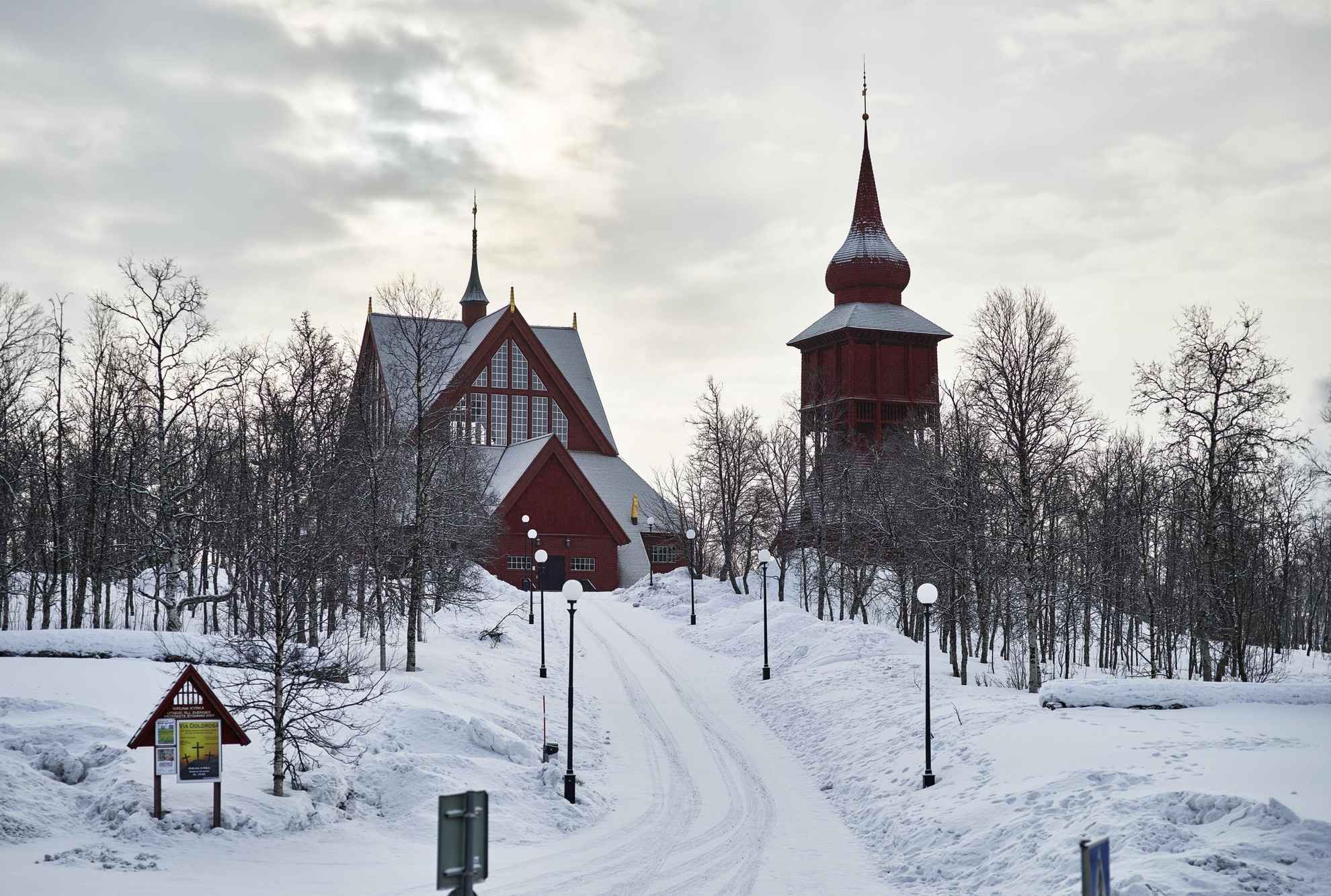 Die Kirche von Kiruna ist ein Holzbau mit einem separaten Glockenturm. Sie liegt an einem schneebedeckten Hang.