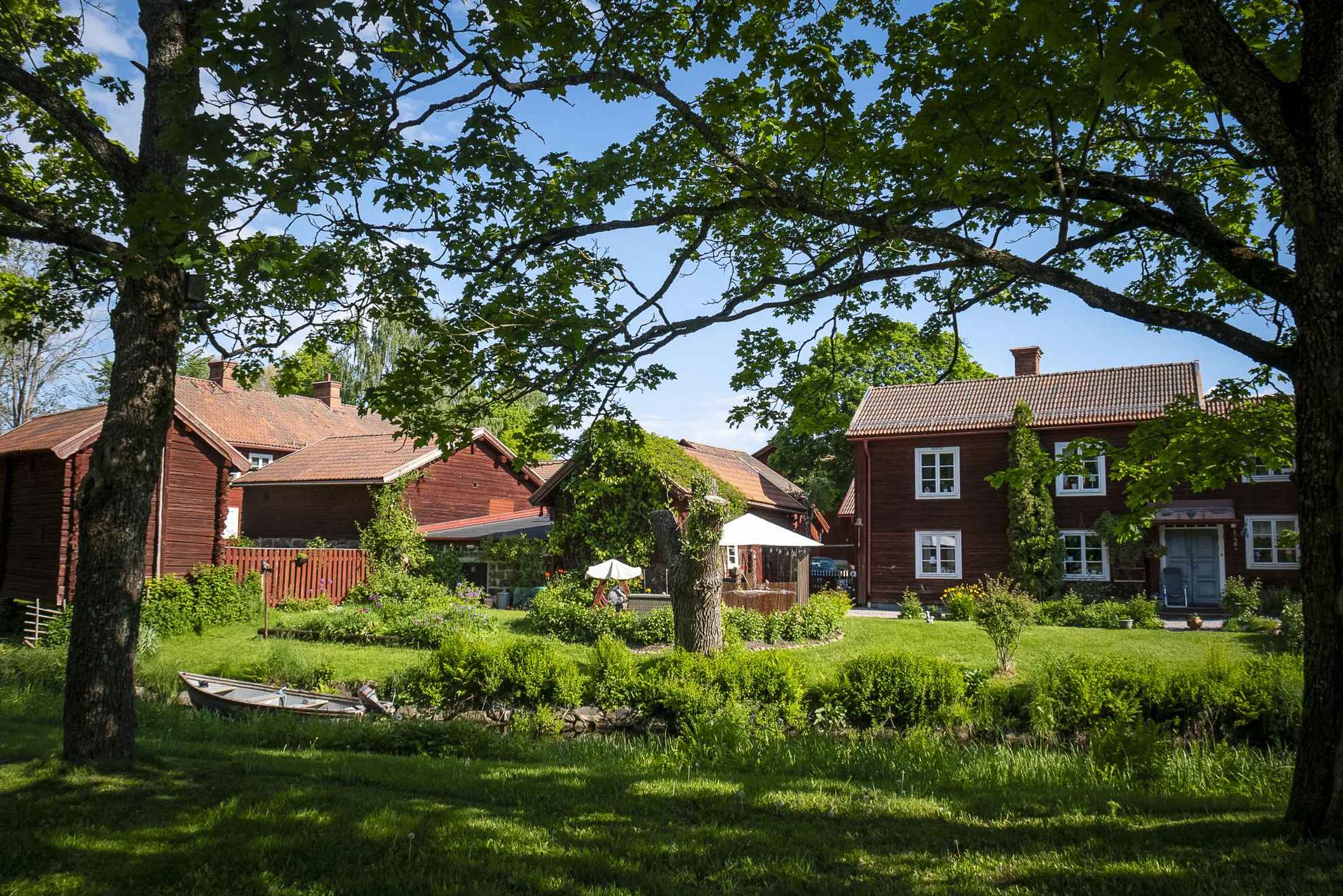 Schwedische Häuser in Falunrot an einem Sommertag in Falun. Die rotgestrichenen Häuser sind von grünen Bäumen umgeben.
