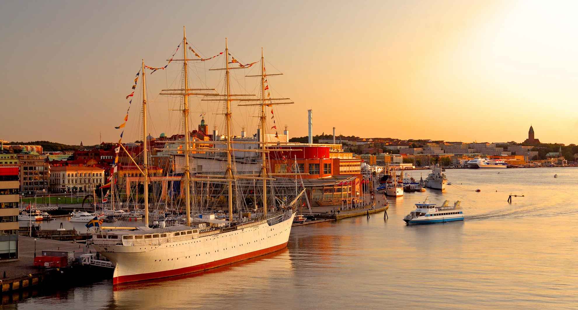 Sunset by the Gothenburg Harbour with large sailing ships, ferries and other boats.