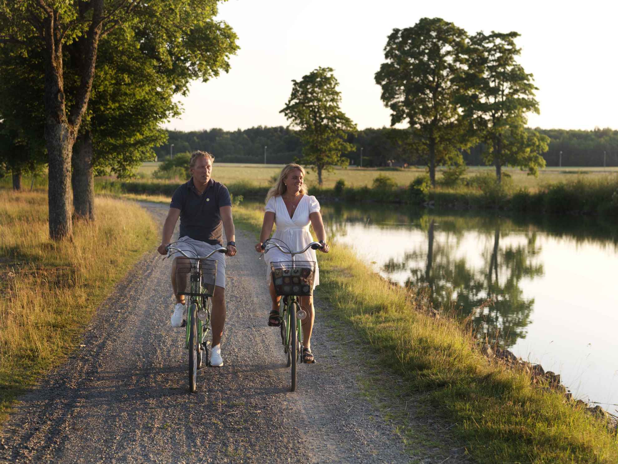 Ein Mann und eine Frau radeln im Sommer neben dem Göta Kanal.