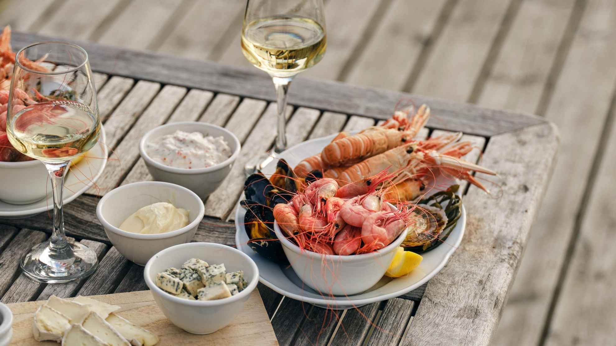 Eine Platte mit Meeresfrüchten und ein Glas Weißwein auf einem Tisch auf einem Steg.