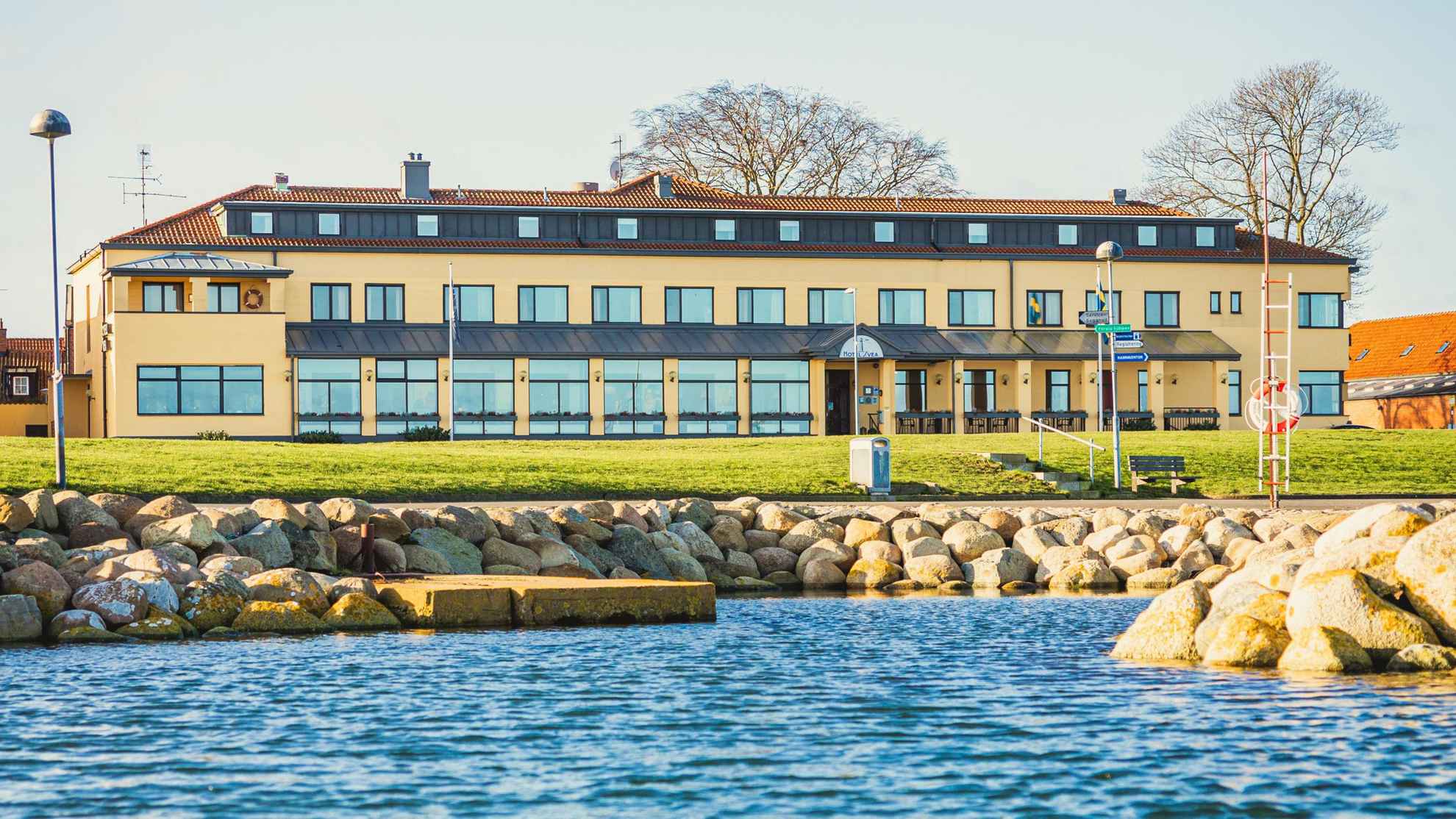 Exterior of Hotel Svea in Simrishamn, Skåne, on a sunny spring day. The yellow building is located by the water.
