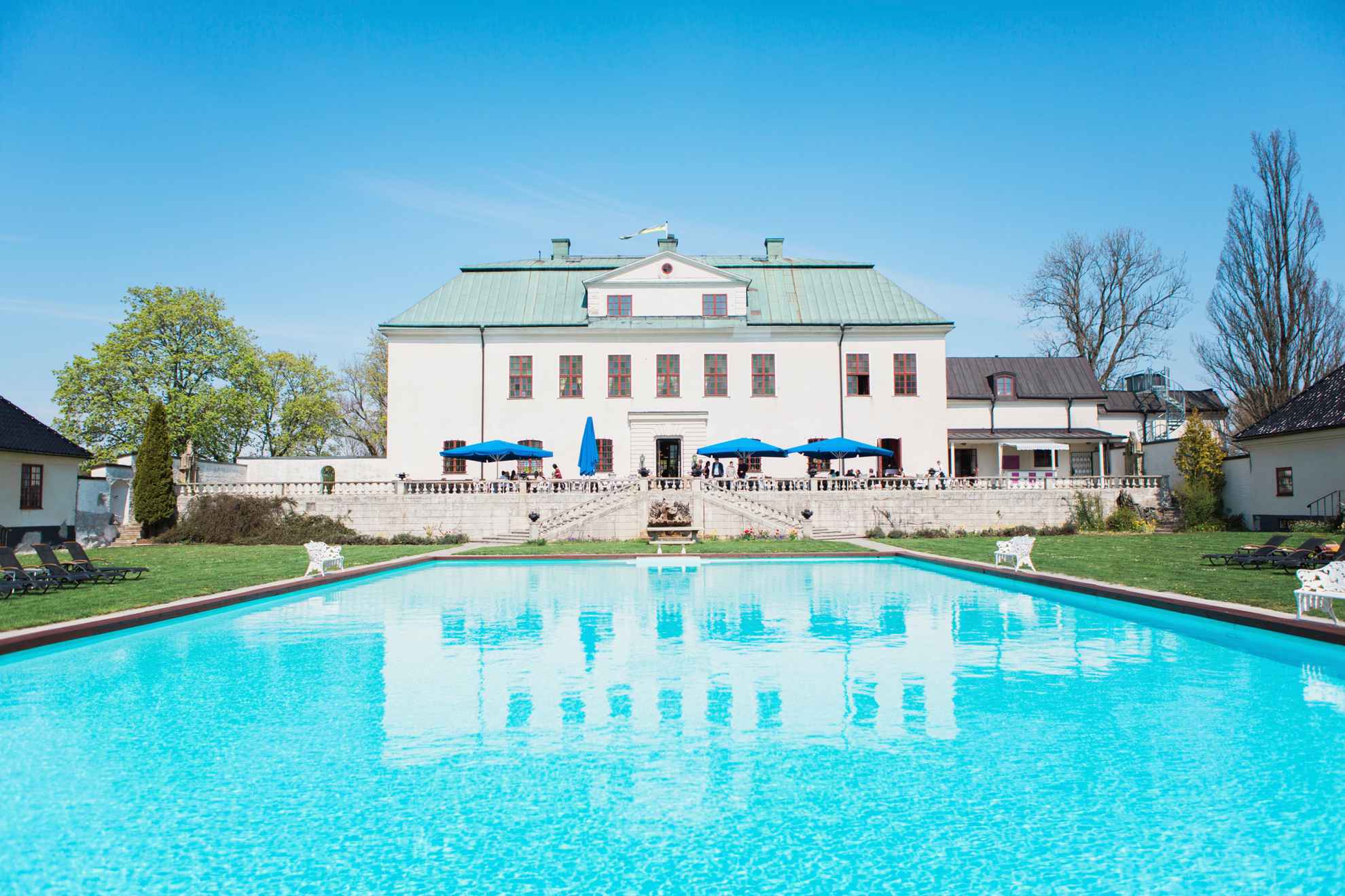 Der Hinterhof von Schloss Häringe mit einem Swimmingpool und einer großen Terrasse.