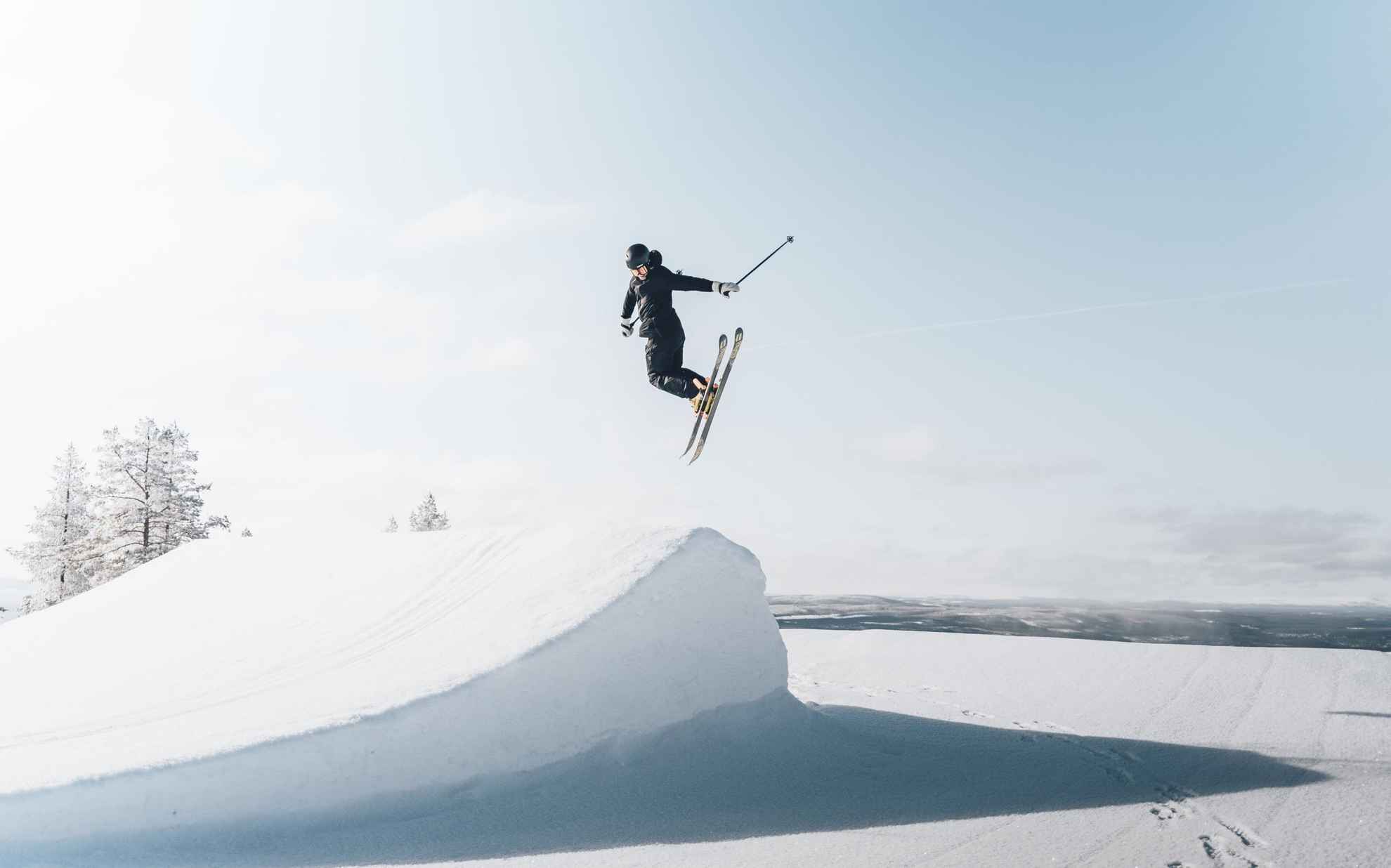 Ein Skifahrer fliegt in der Luft über einer Schneerampe.