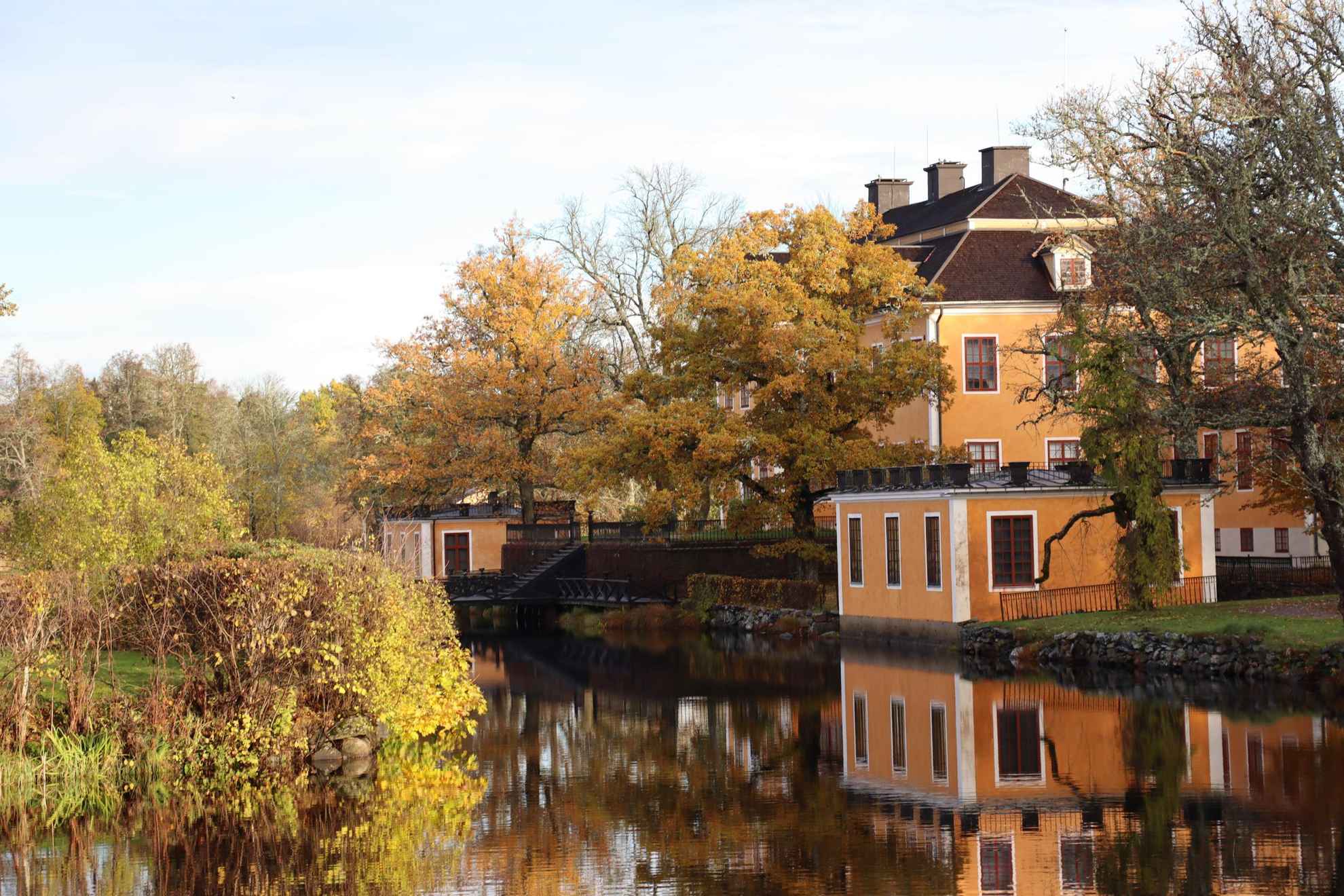 Die Häuser von Lövstabruk mit orangefarbener Fassade und weißen Verzierungen neben dem Wasser.