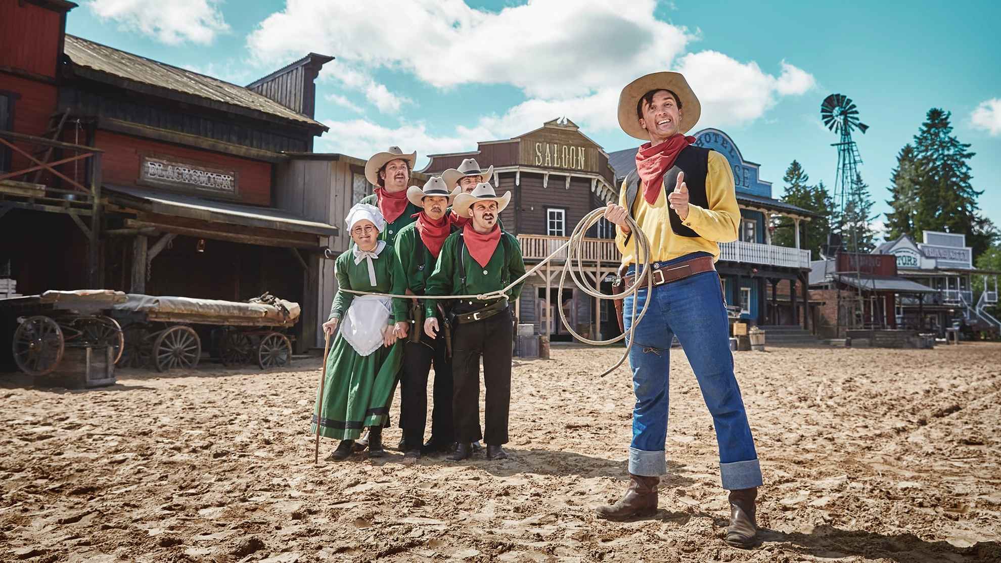 Ein Mann, der als Lucky Luke verkleidet ist, hält ein Lasso um eine Gruppe anderer kostümierter Figuren im High Chaparral in Småland.