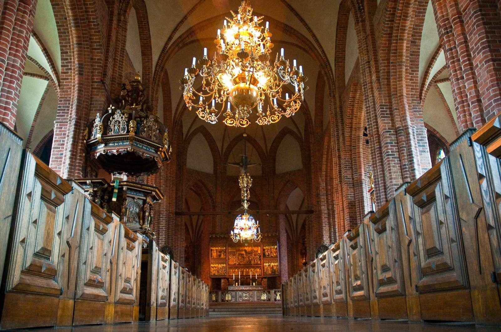 Im Inneren eine große Kirche im gotischen Stil. Das Podium geradeaus und zwei große Kronleuchter hängen von der Decke.