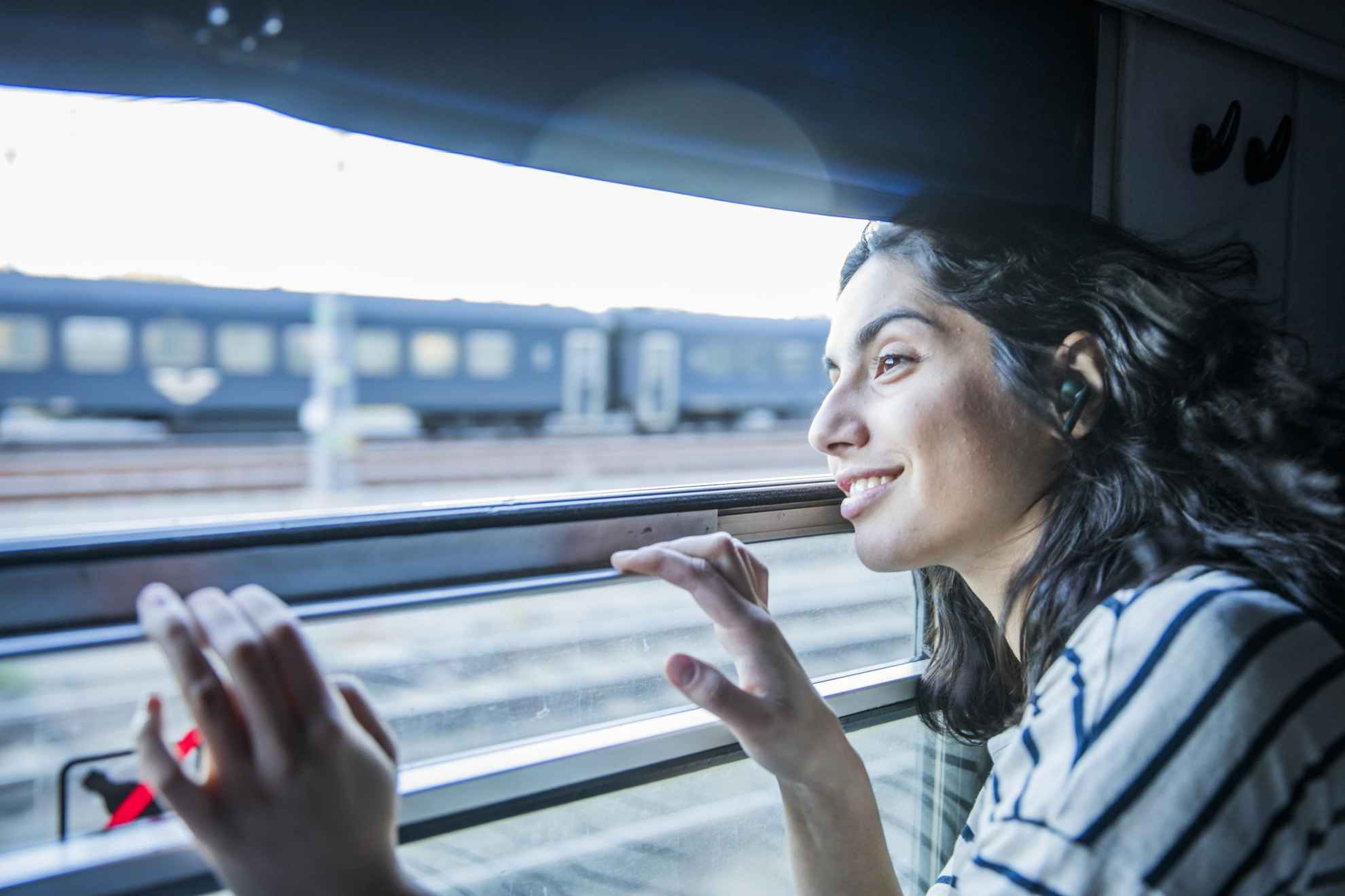 Eine Frau schaut aus dem Fenster eines Zuges, der gerade einen anderen Zug überholt.