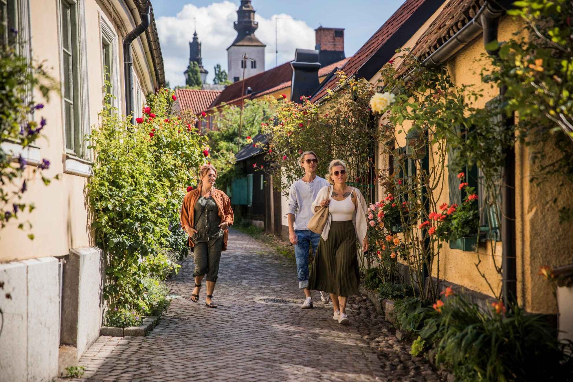 Menschen laufen entlang bunter Häuser durch die Straßen Visbys.
