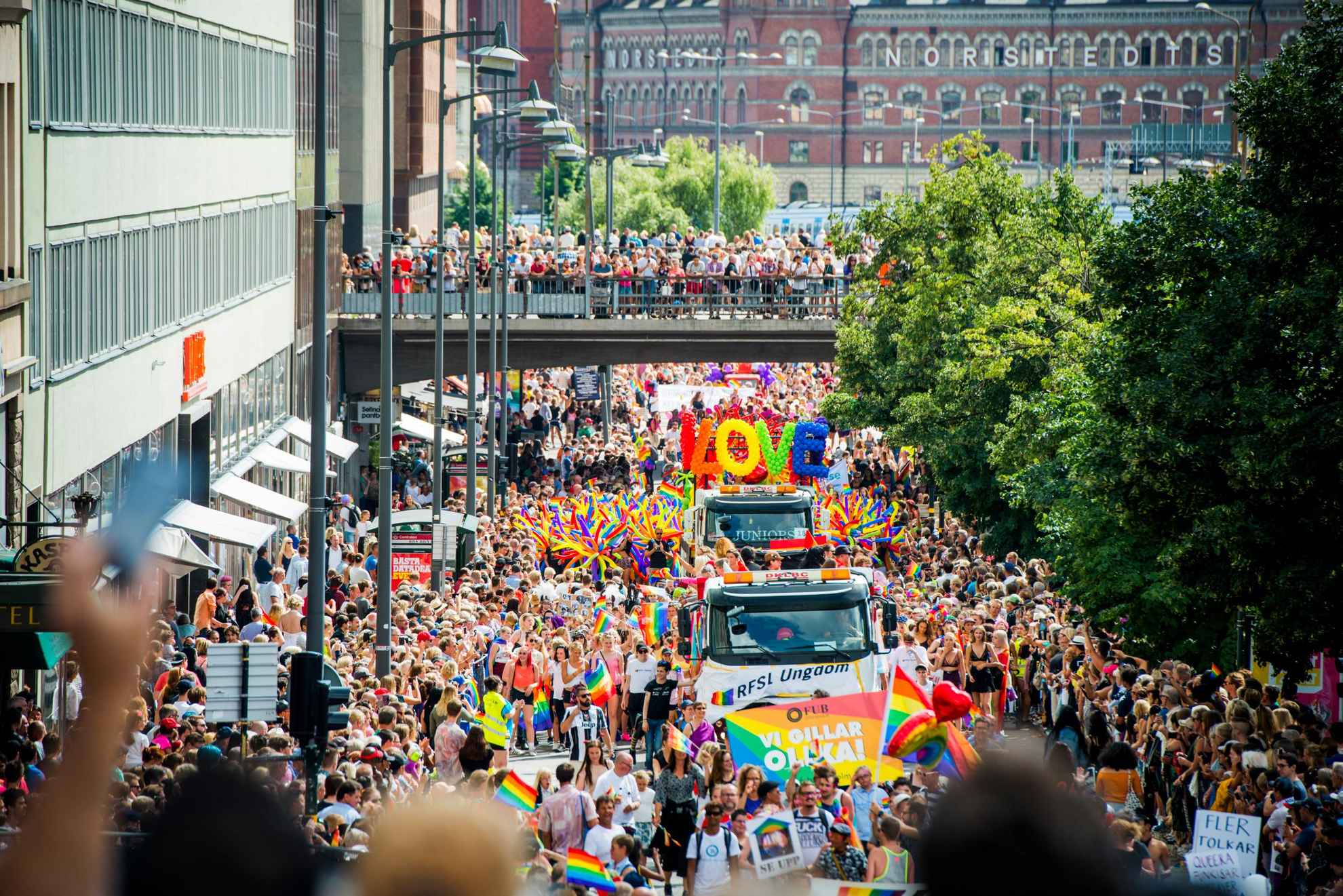 Zahlreiche Besuchende mit bunten Fahnen bei dem Pride Umzug in Stockholm.
