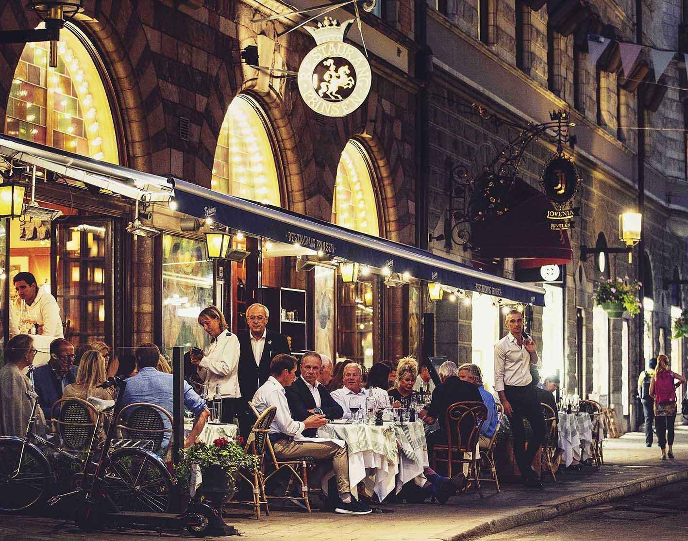 Der von Restaurantgästen gefüllte Außenbereich des Restaurants Prinsen in Stockholm an einem Sommerabend.