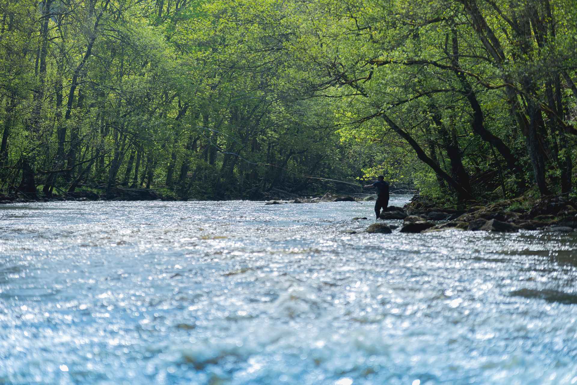 Eine Person angelt im Fluss Örekil. Der Fluss ist von Grünflächen umgeben.