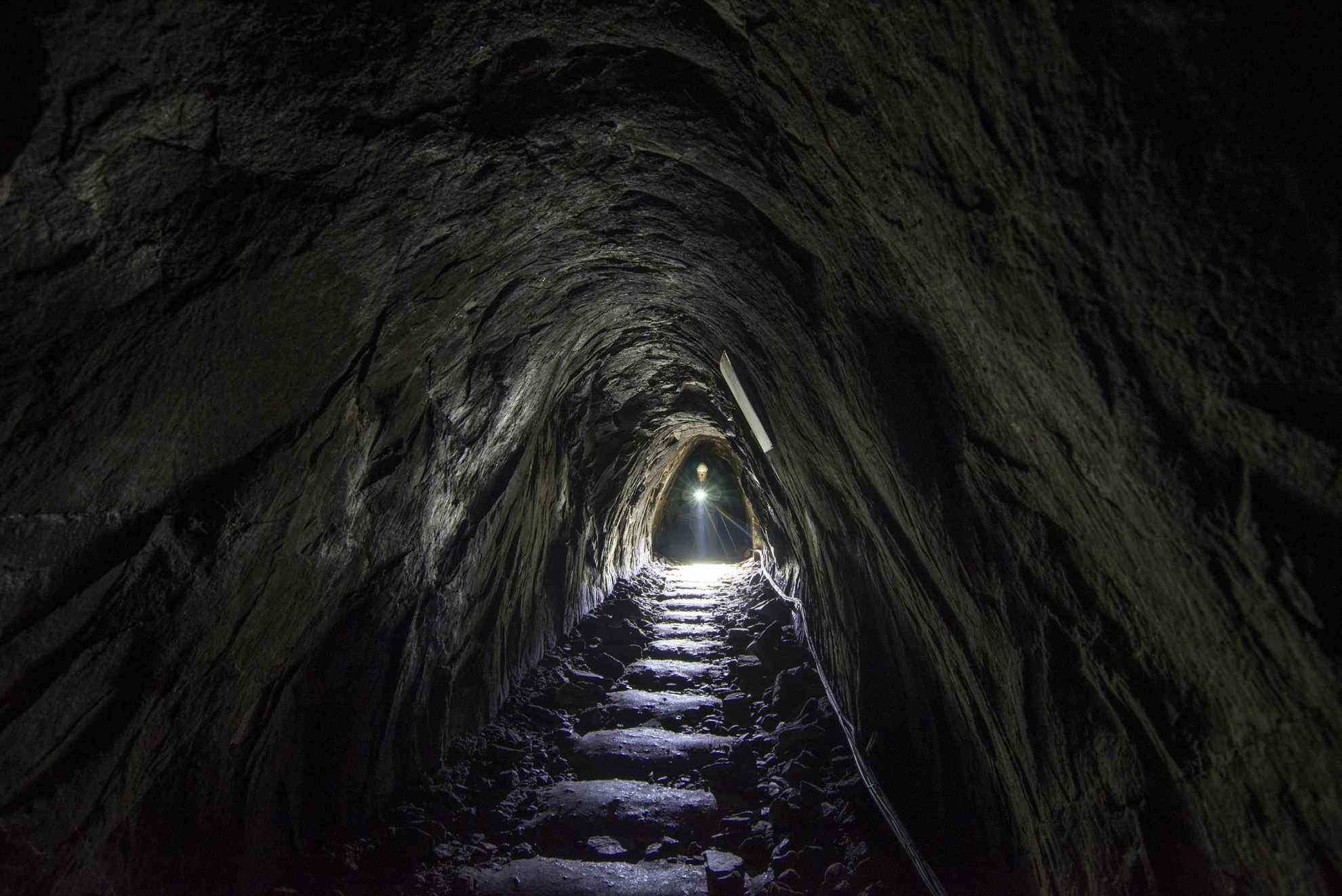 Eine Person mit einer Taschenlampe geht durch einen unterirdischen Gang in der Silbermine Sala.