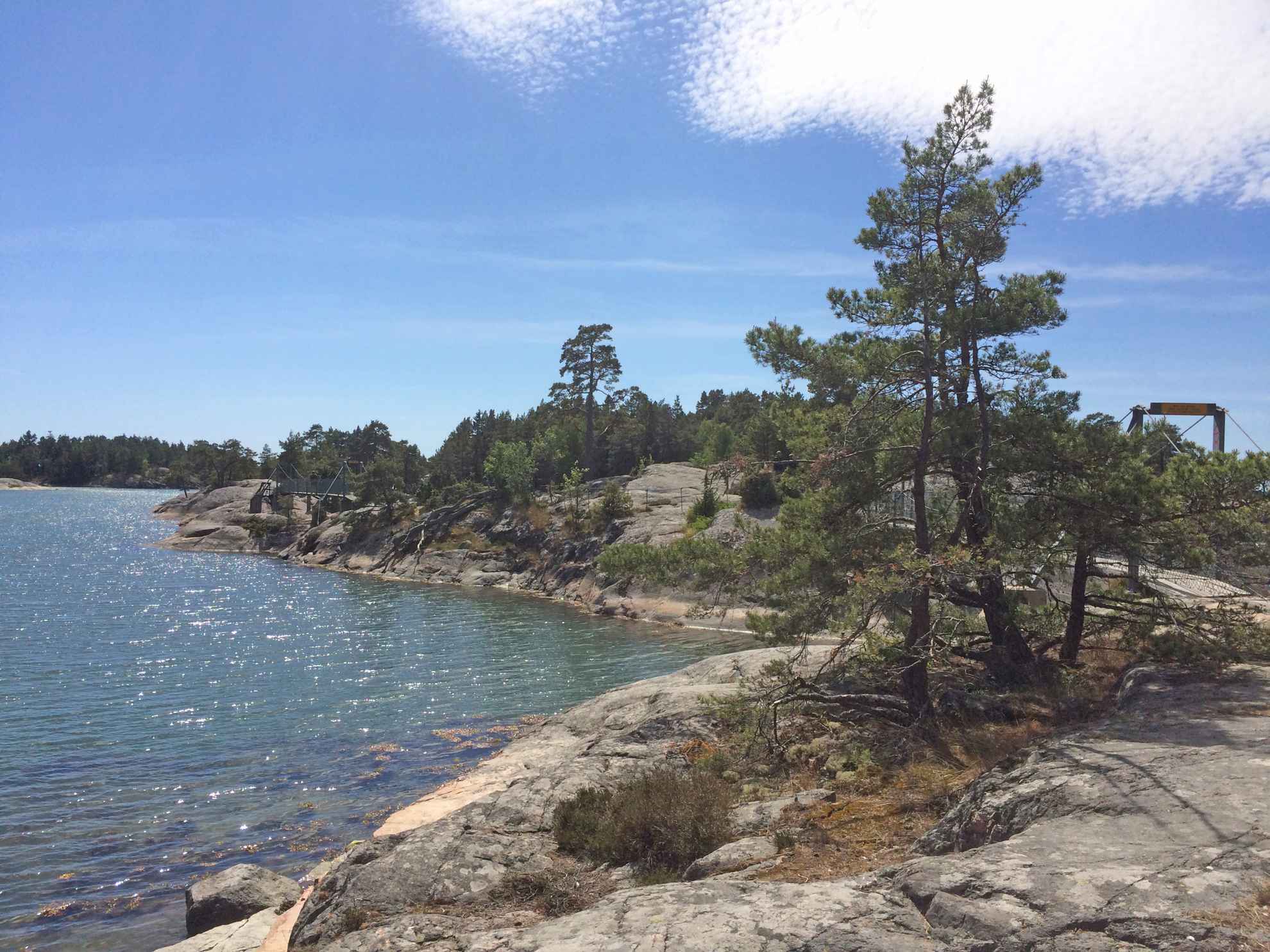 Bäume wachsen auf Felsen, Wasser auf der linken Seite. Hinter den Bäumen kann man kaum die kleinen Brücken erkennen, die die felsigen Inseln verbinden.