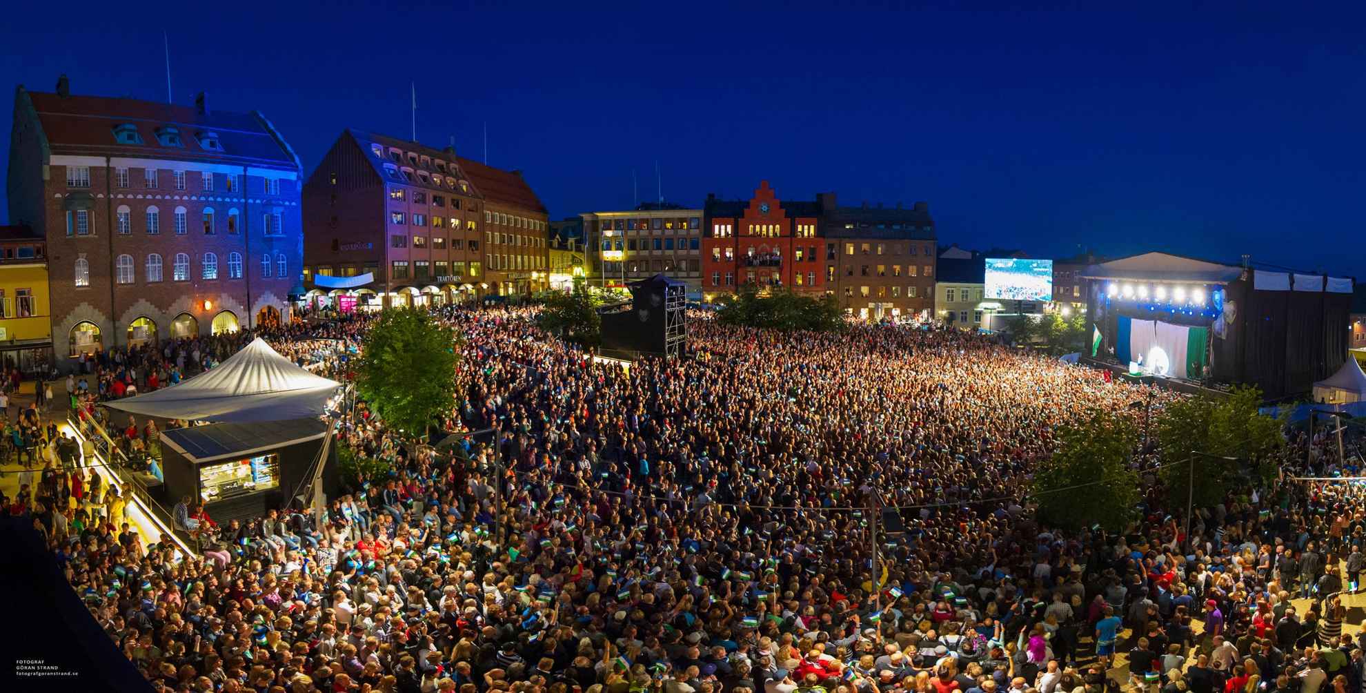 Zahlreiche Besuchende stehen auf einem Platz in Östersund und genießen das dort stattfindende Konzert.