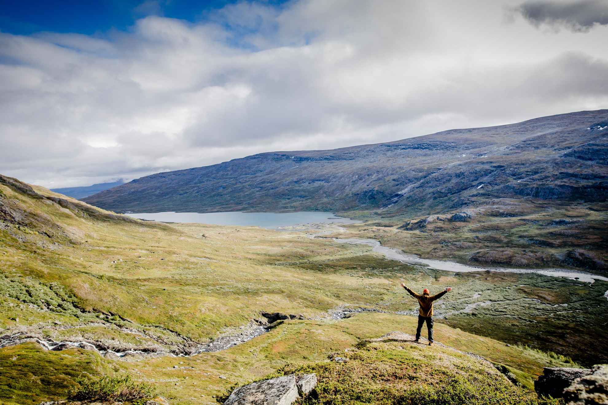 Eine Person steht in der Natur in Schwedisch Lappland und hebt die Arme Richtung Himmel.