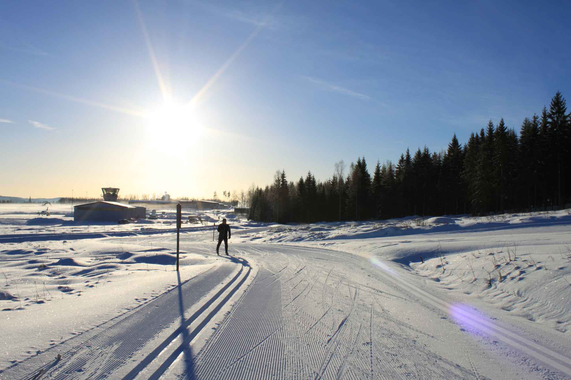 Eine Person fährt Ski an einem sonnigen Wintertag in Torsby