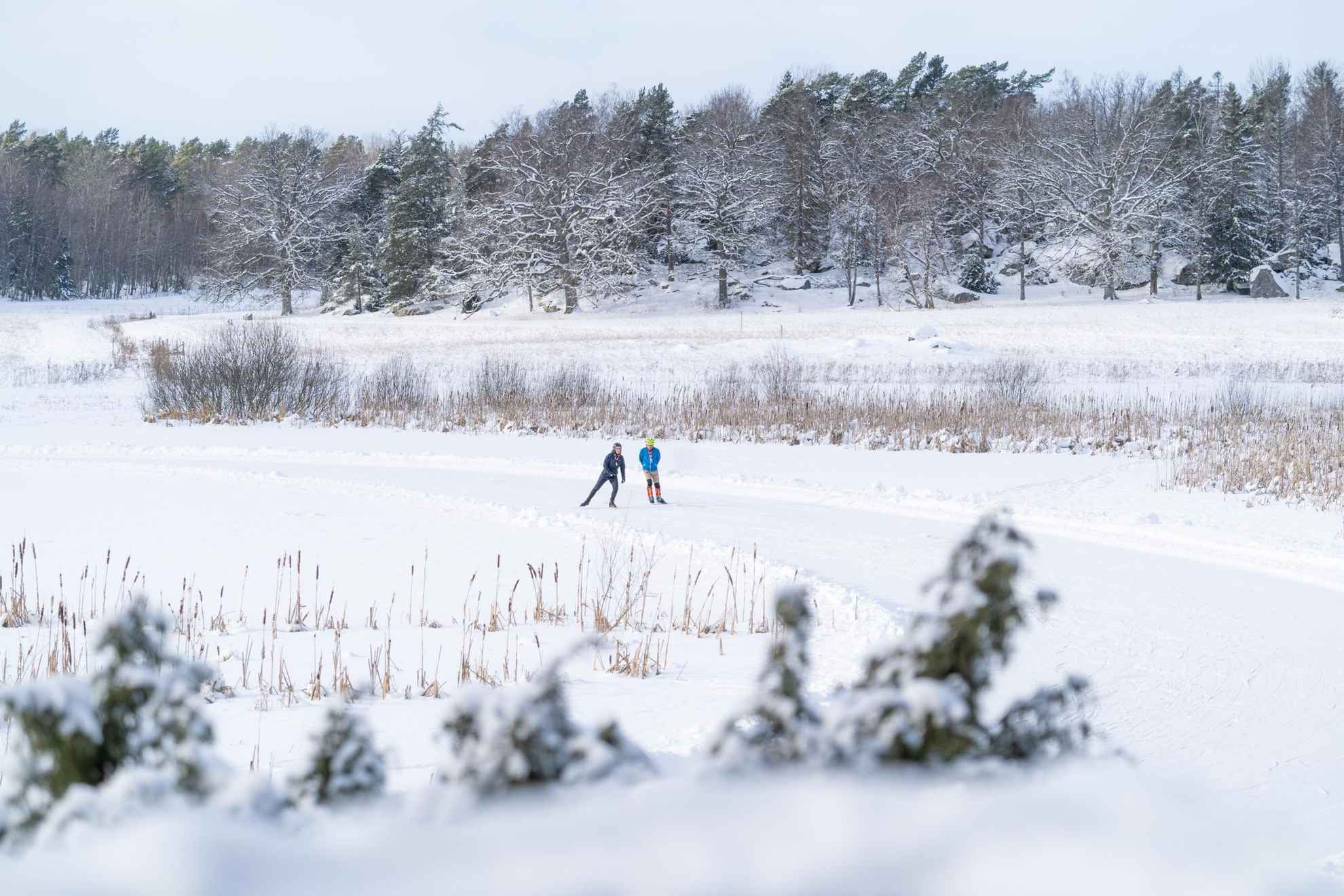 Eine schneebedeckte Fläche und zwei-Personen beim Eislaufen.