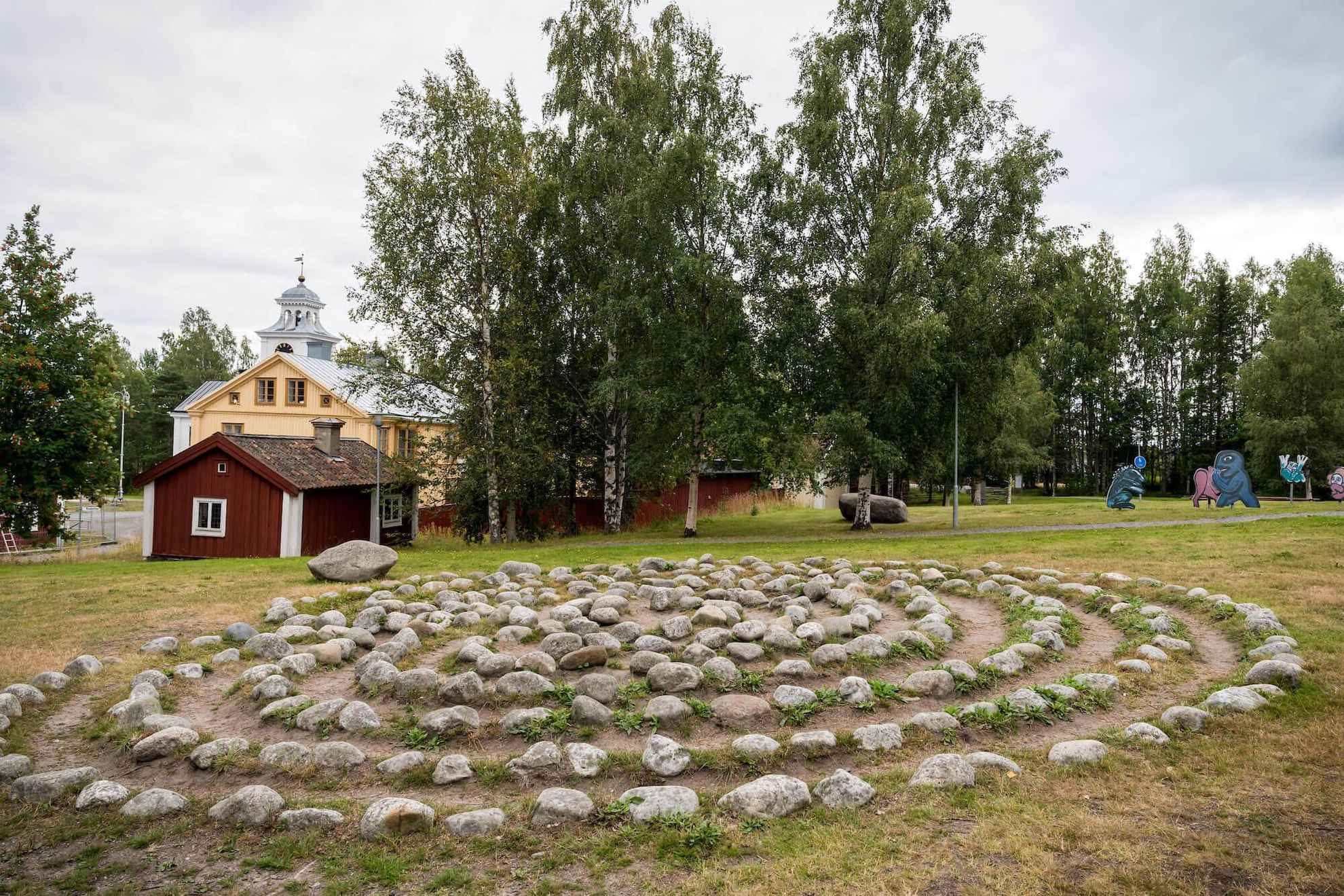 Steine, die in einem Kreis angeordnet sind, der ein Labyrinth in einem von Grün umgebenen Park bildet.
