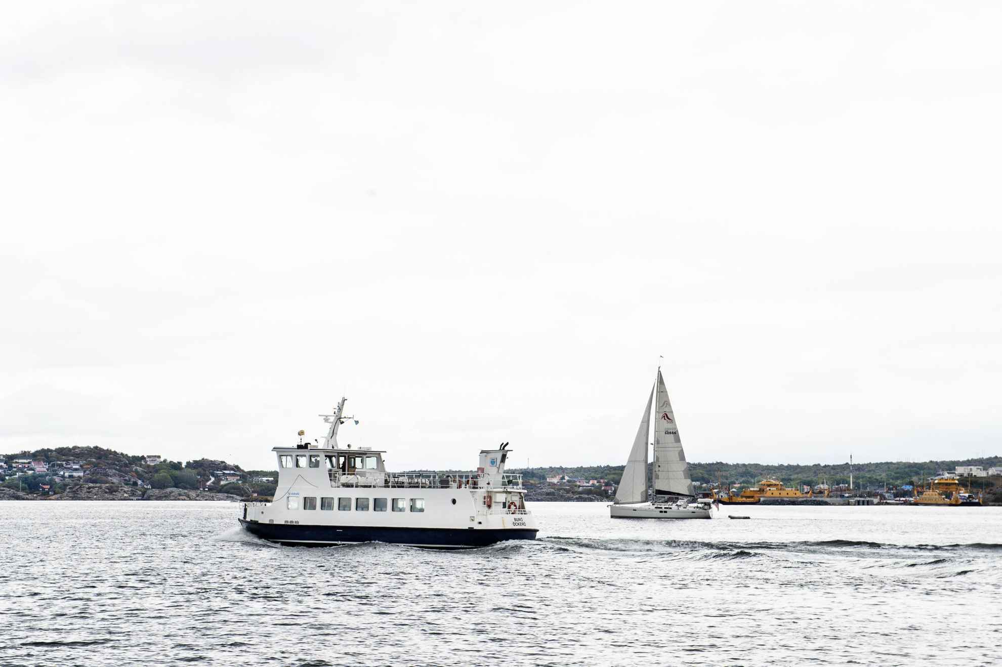 Eine kleine Fähre und ein Segelboot auf dem Meer bei einer Insel vor Göteborg.