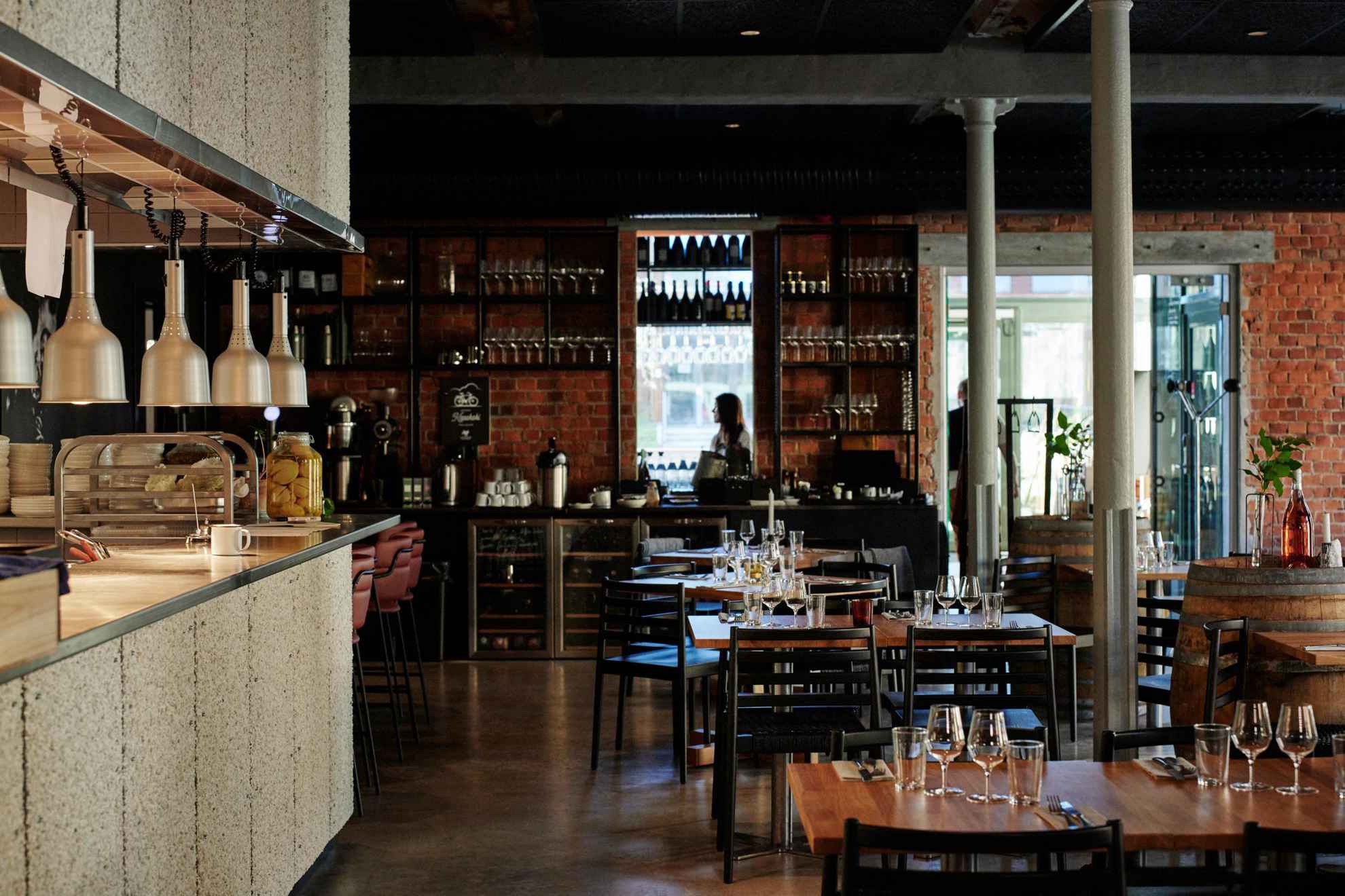 Innenraum eines Weinrestaurants mit mehreren Tischen und einer Bar auf der linken Seite.