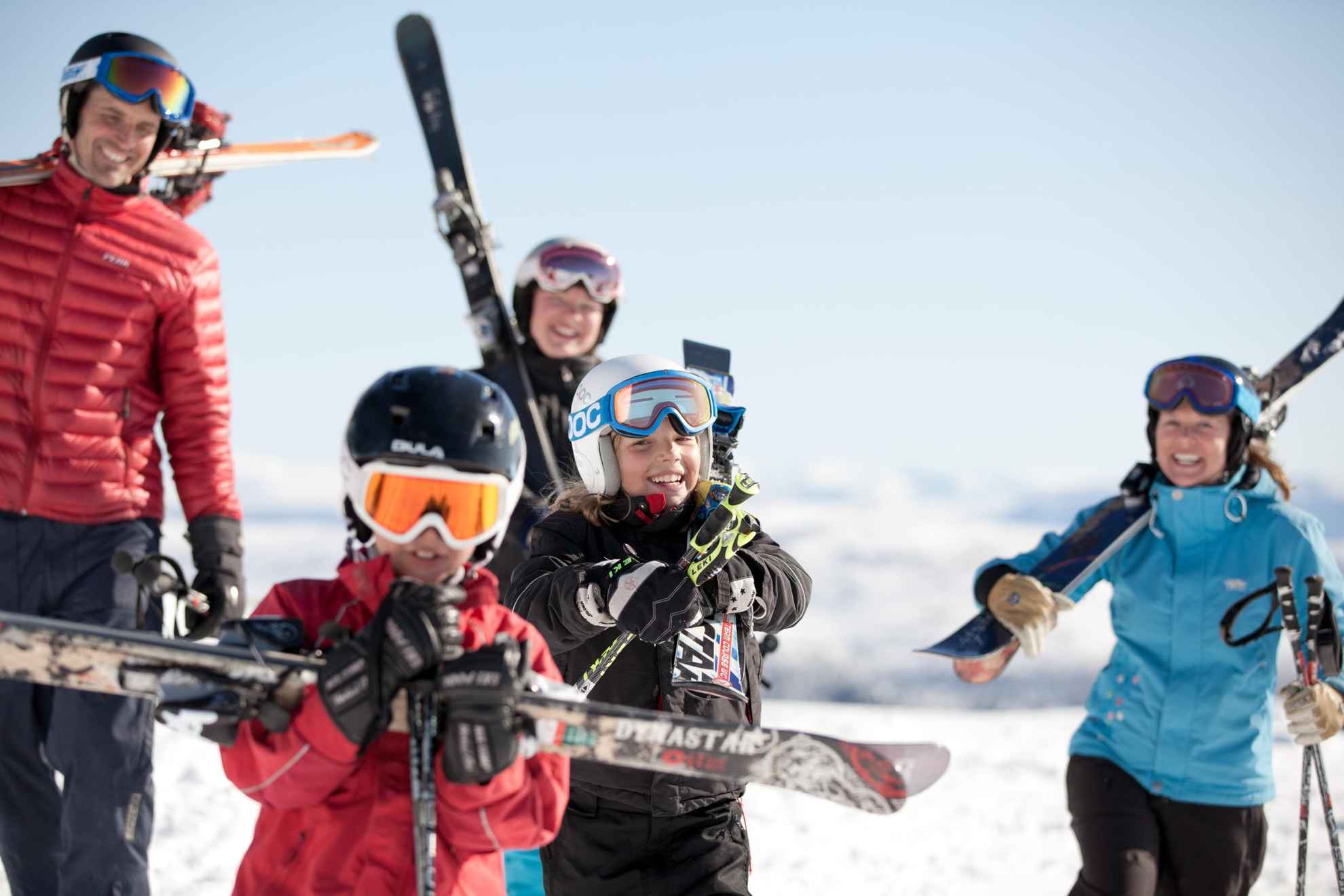 Eine Familie steht mit Skiern und Winterkleidung  ausgerüstet in einer Schneelandschaft.