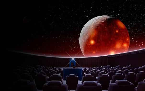 Eine große Kinoleinwand im Inneren von Wisdone zeigt einen Planeten im Weltraum.