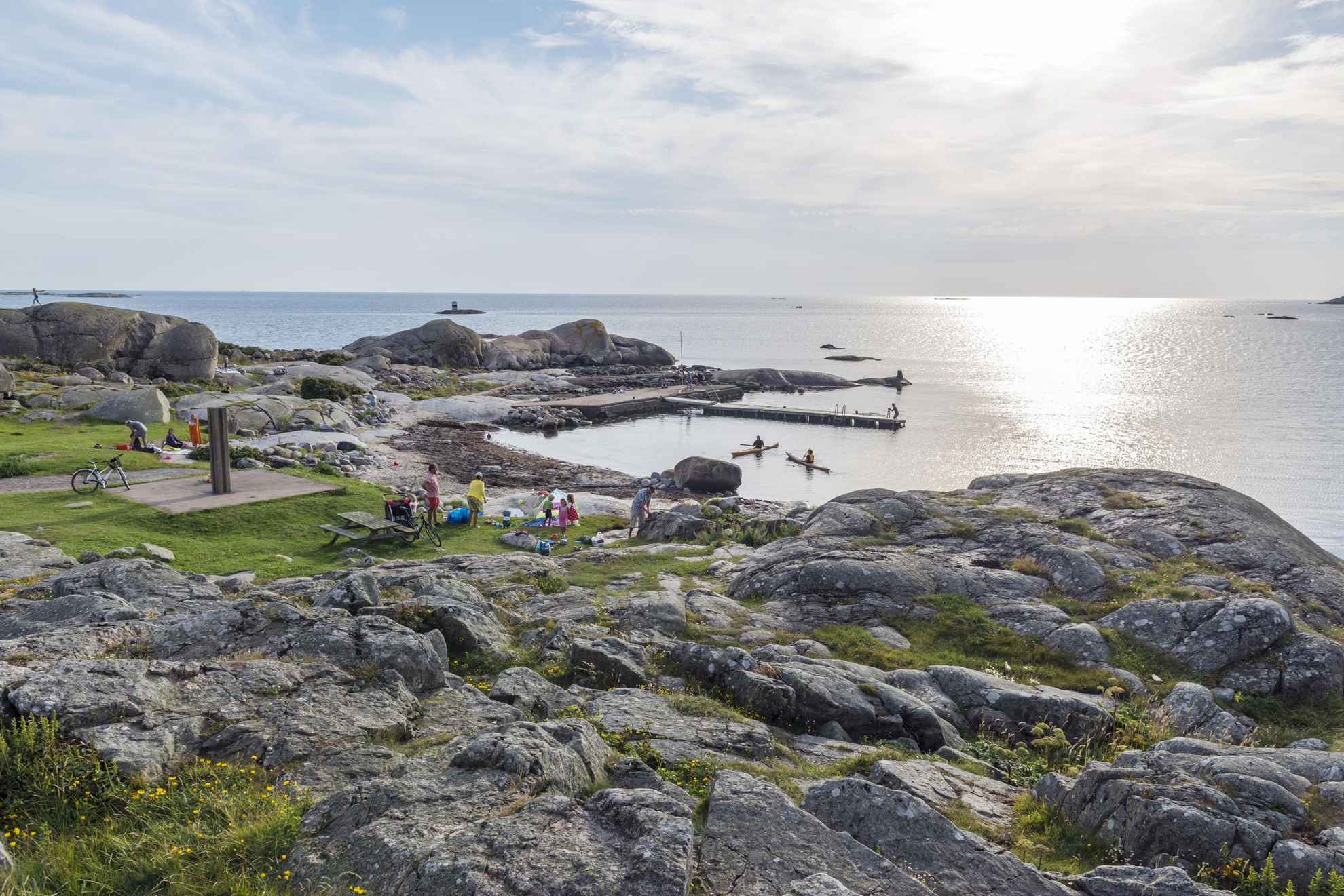 Ein felsiger Strand auf der Insel Hönö in den Schären von Göteborg. Menschen besuchen den Strand. Im Wasser sind Kajak-Fahrer