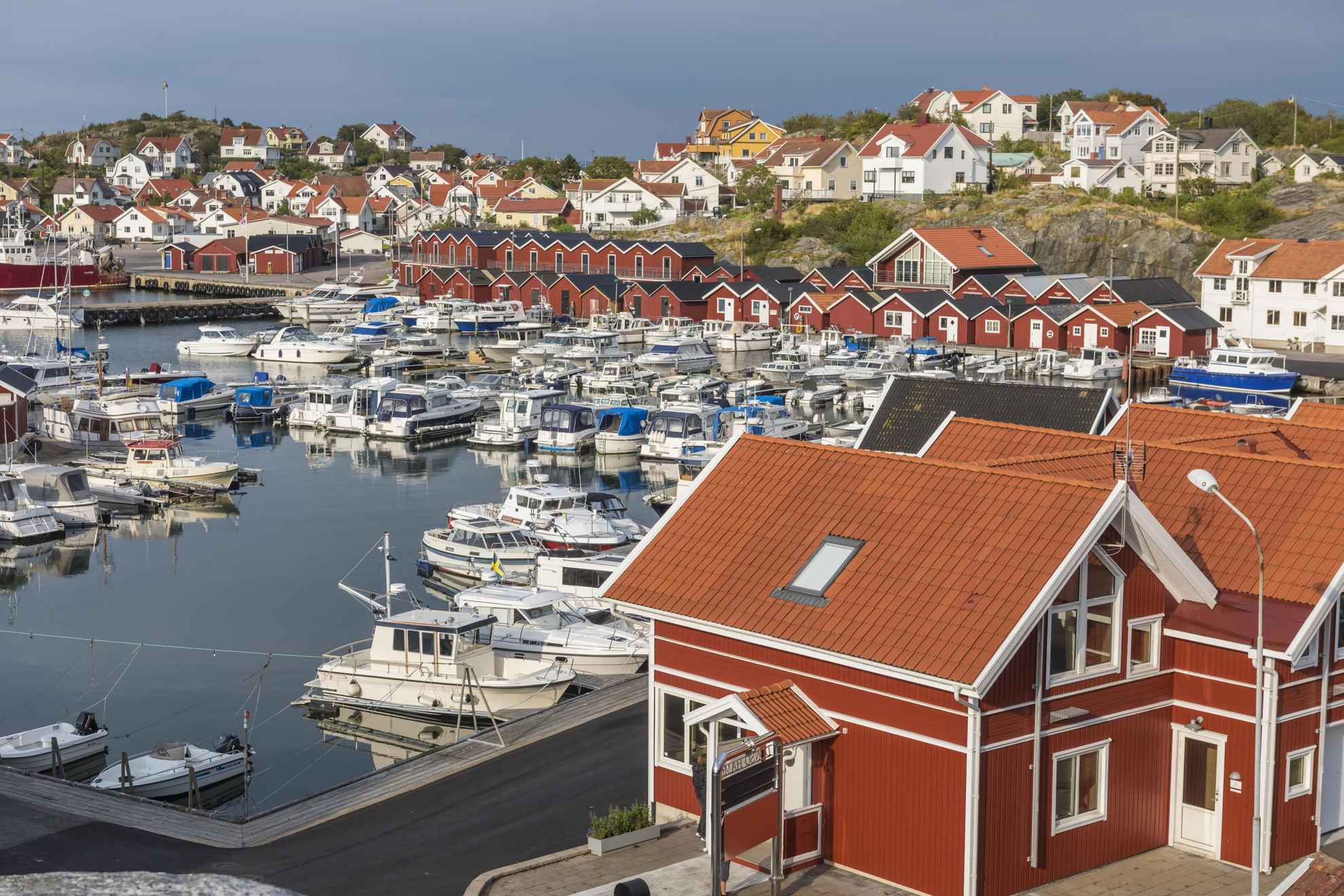 Ein Hafen mit Booten, roten Fischerhütten und weißen Häusern.