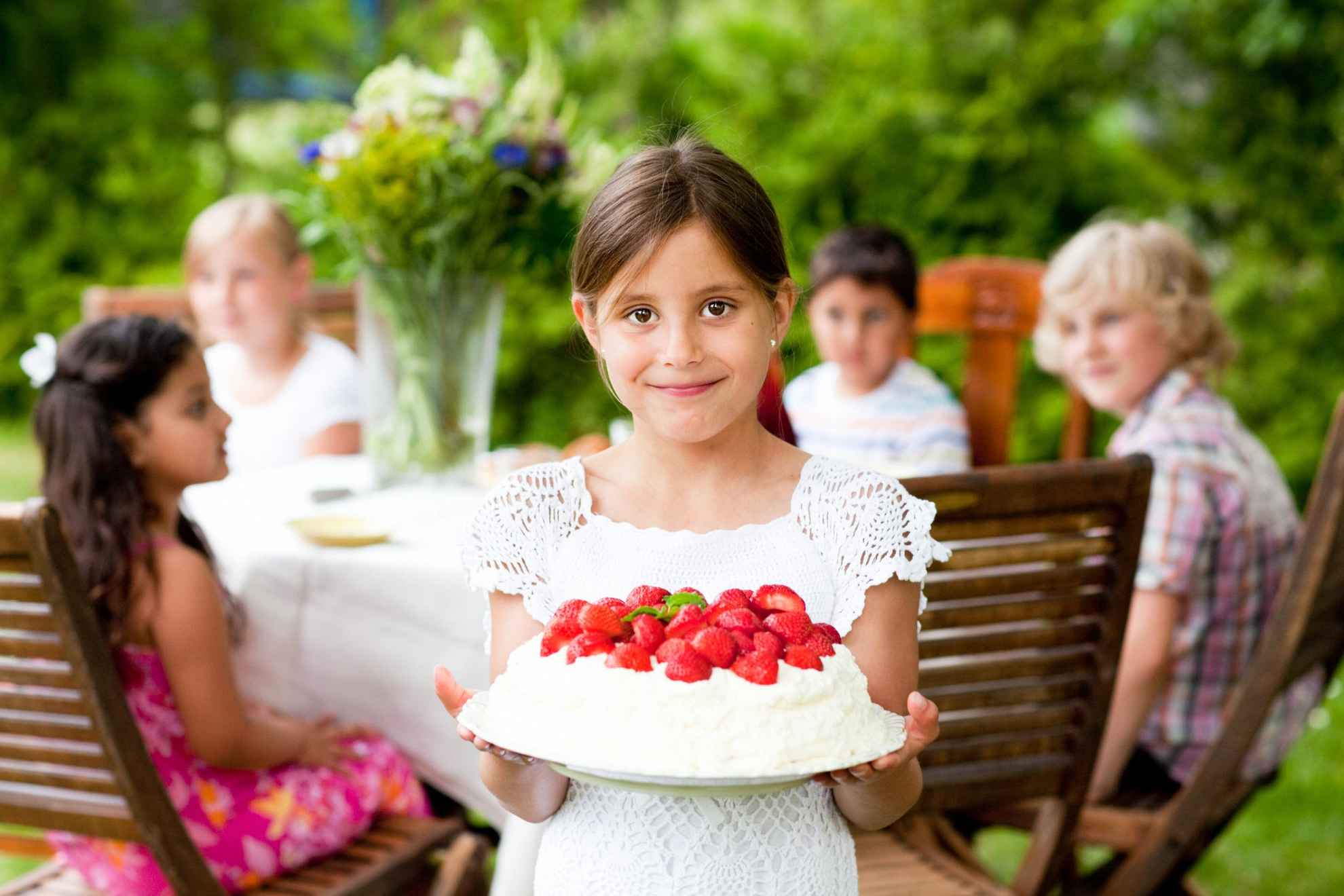 Ein Mädchen hält eine Erdbeertorte in der Hand.