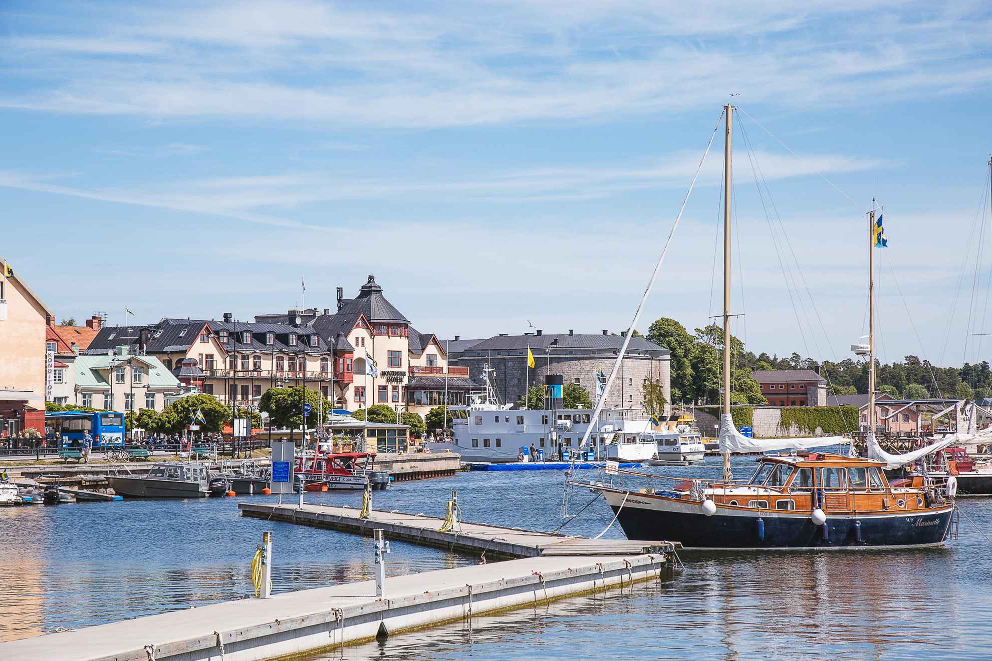 Ein Hafen in den Stockholmer Schären, in dem ein Holzboot und ein Ausflugsschiff anlegen.