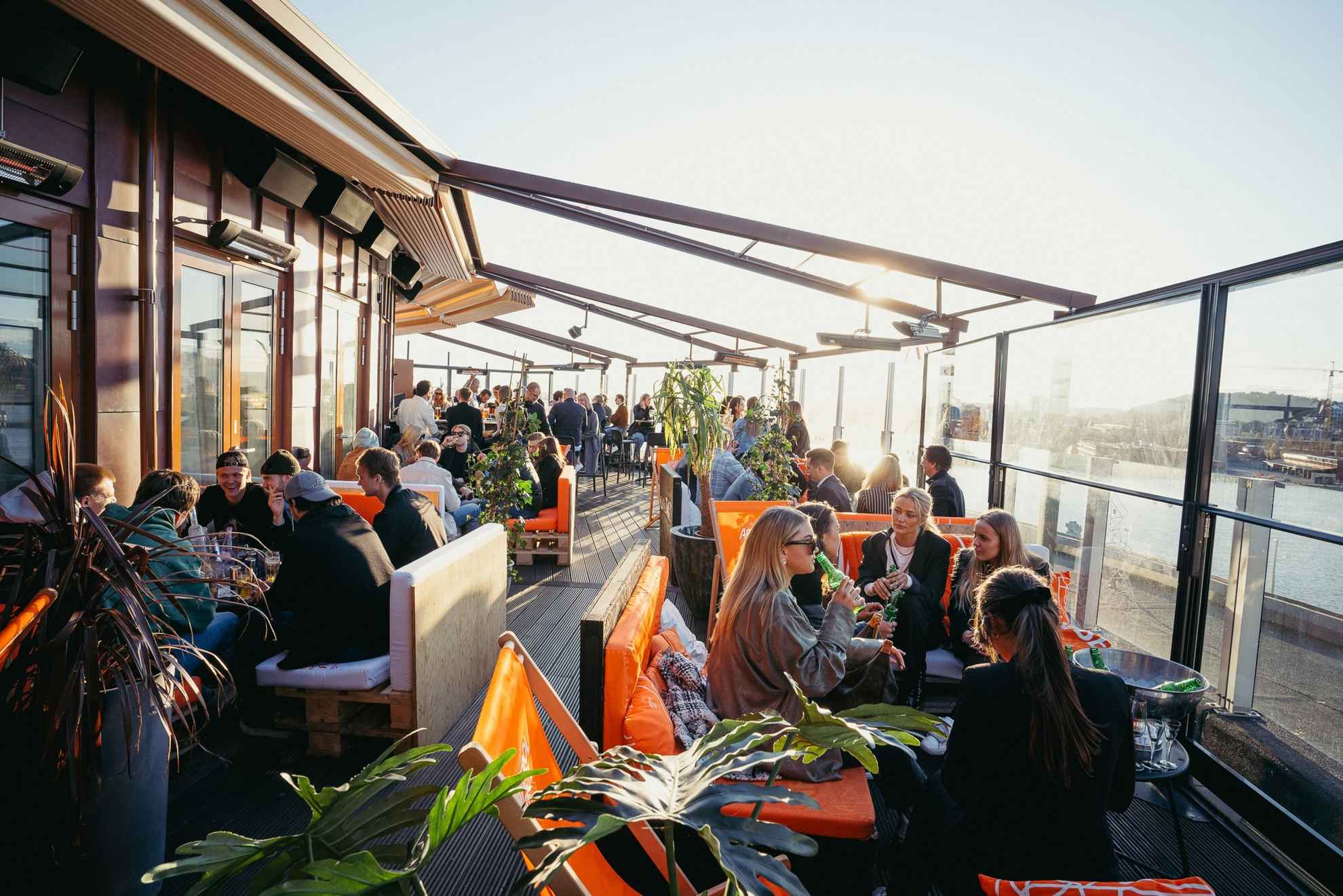 Auf der Dachterrasse des Taket in Göteborg sitzen Menschen und genießen Getränke und die Gesellschaft von Freunden.