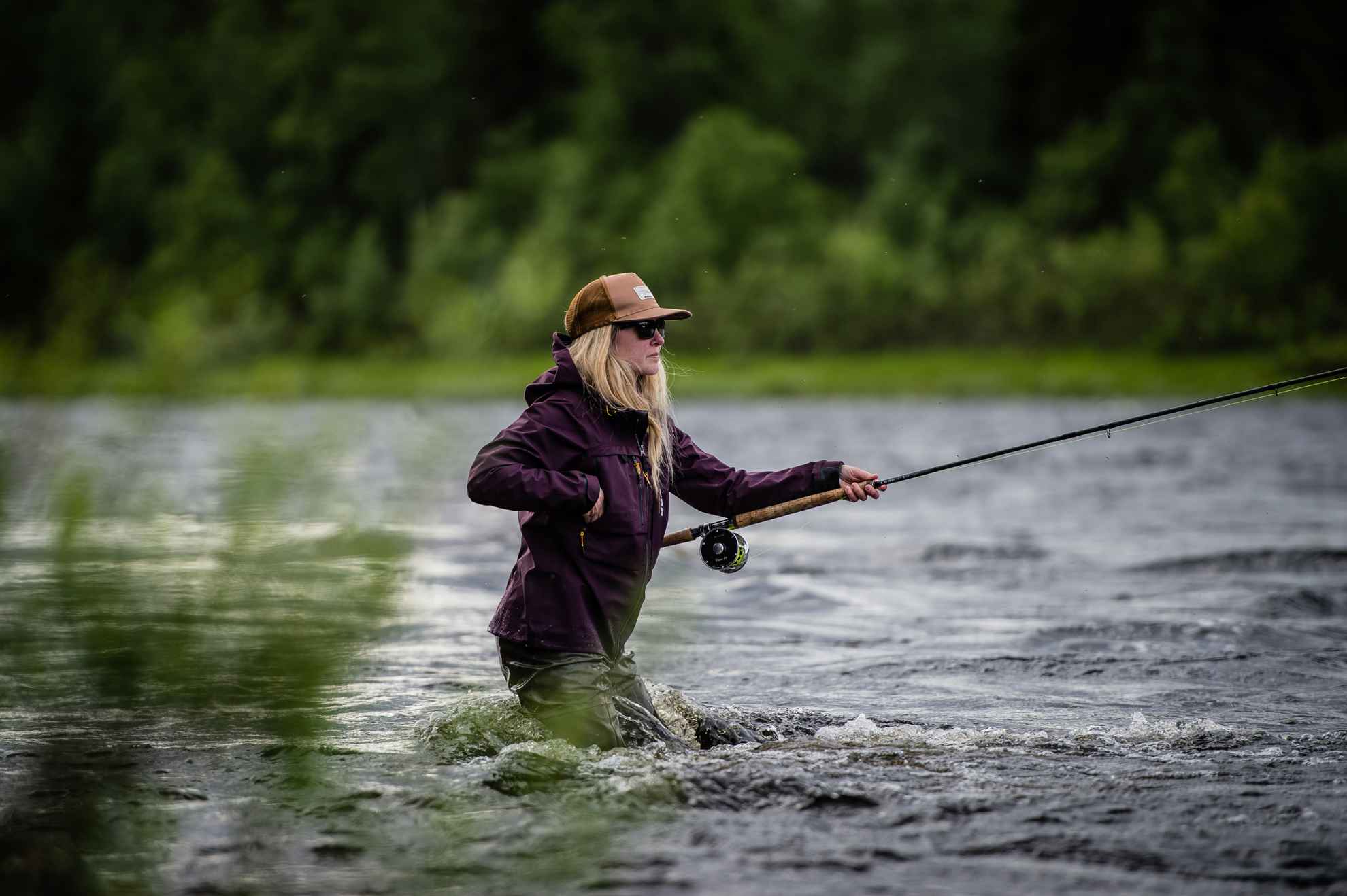 Eine Fliegenfischerin in einem Fluss in Schwedisch Lappland.