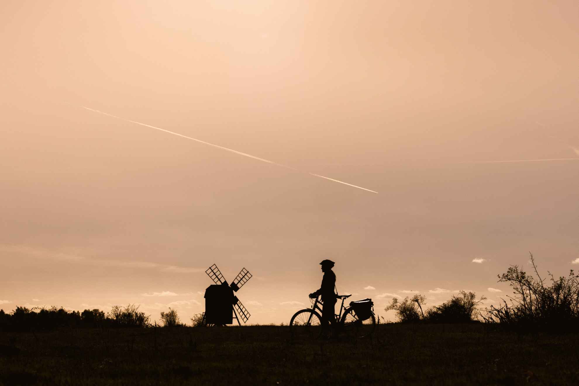 Silhouette of a cyclist at dusk with a windmill in the background