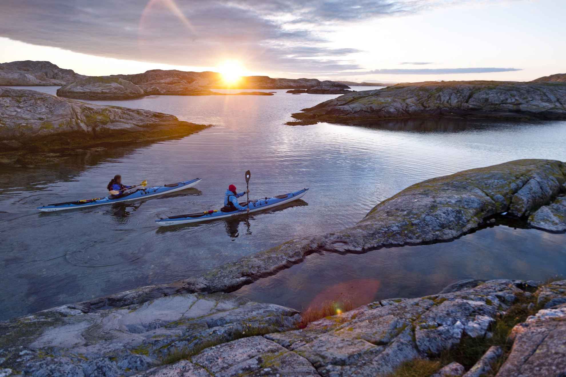 Two kayaks make their way past islands of the Bohuslän coast as the sun sets.