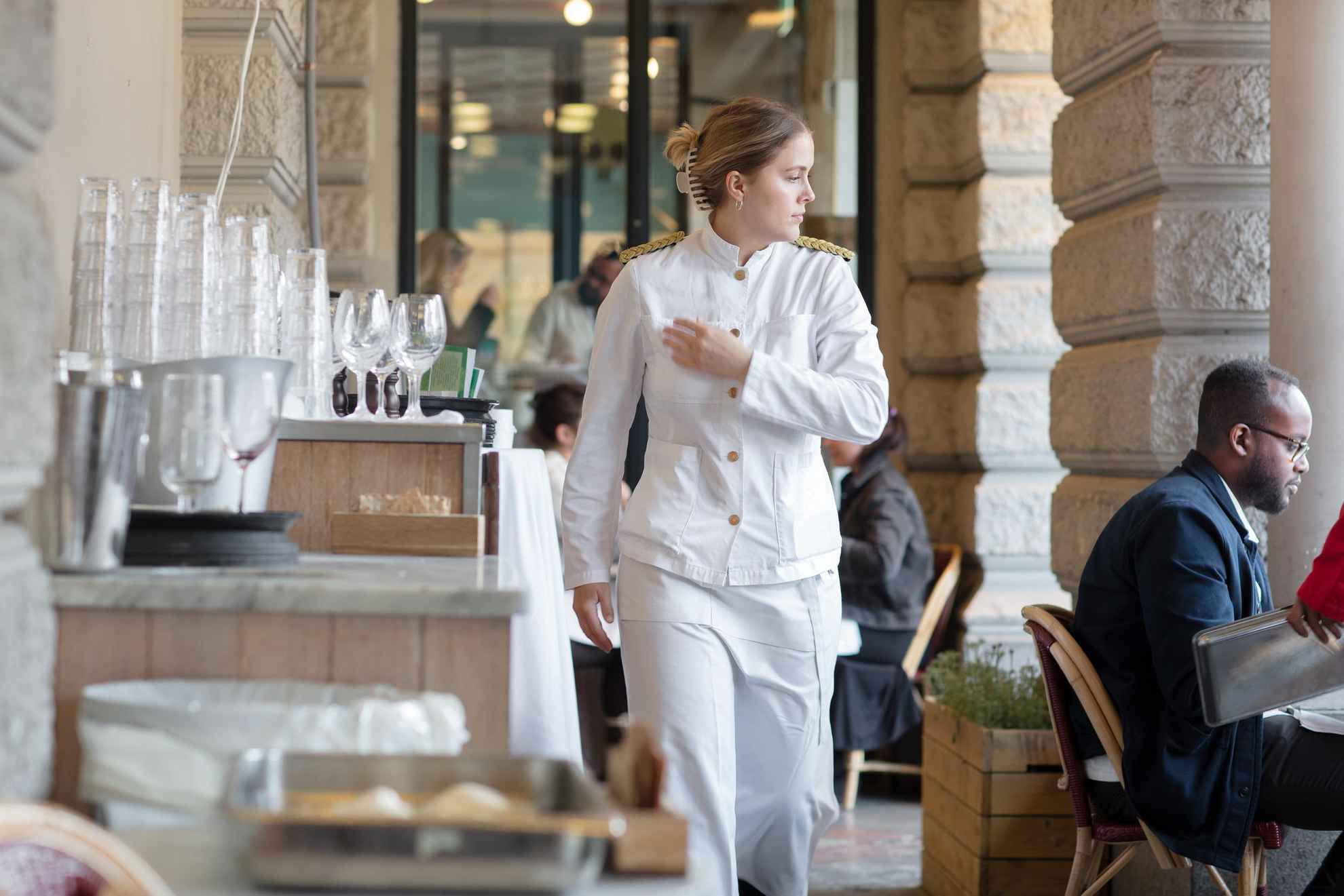 Eine weiß gekleidete Kellnerin geht durch das Restaurant Sturehof.