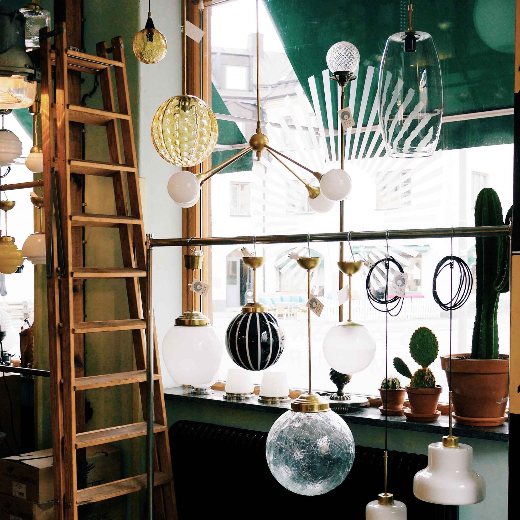 Mehrere verschiedene Glaslampen hängen im Schaufenster des Designshops Svenska Armaturer.