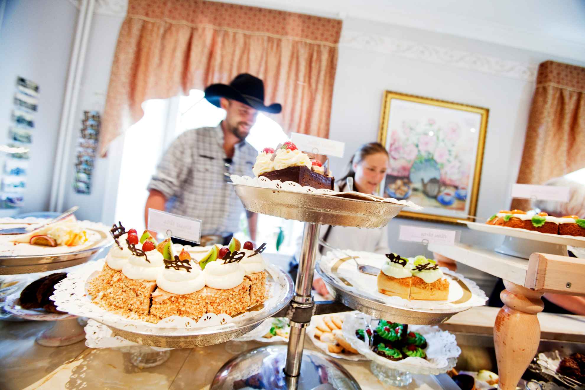 Eine Person steht vor einem Tisch voller Kuchen.